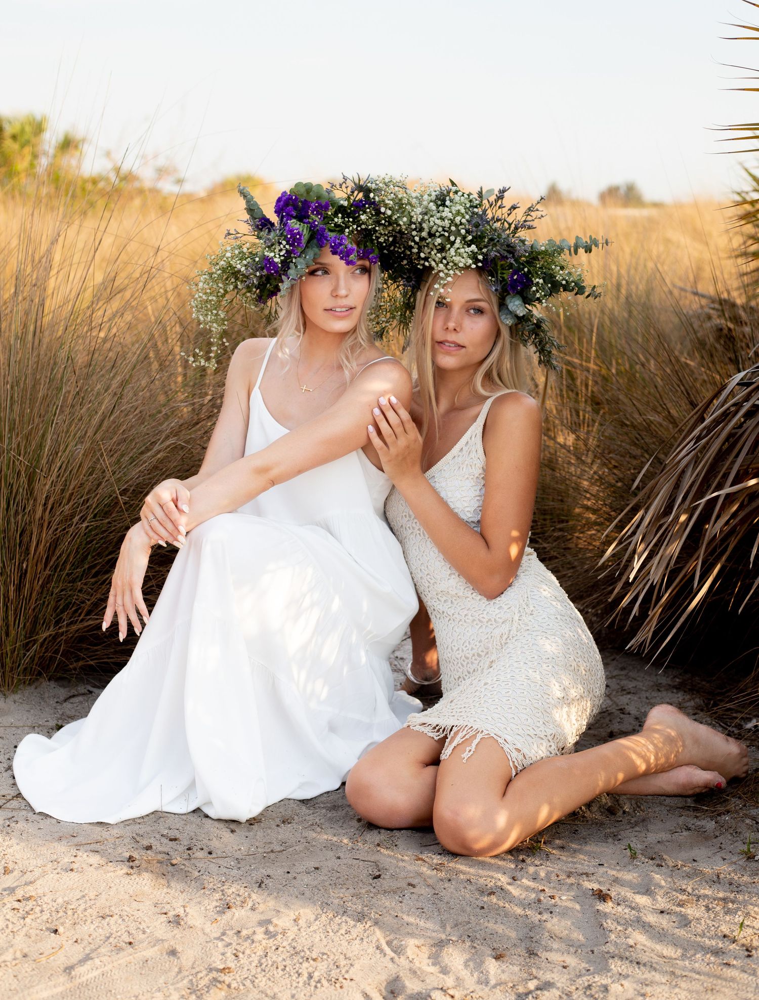 Artistic beach portrait with white dresses and wildflower crowns in evening light.