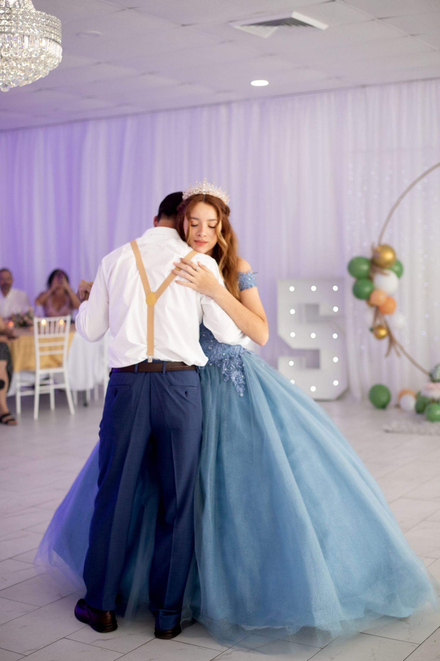 Dancing scene in purple-lit venue with flowing blue tulle ballgown.