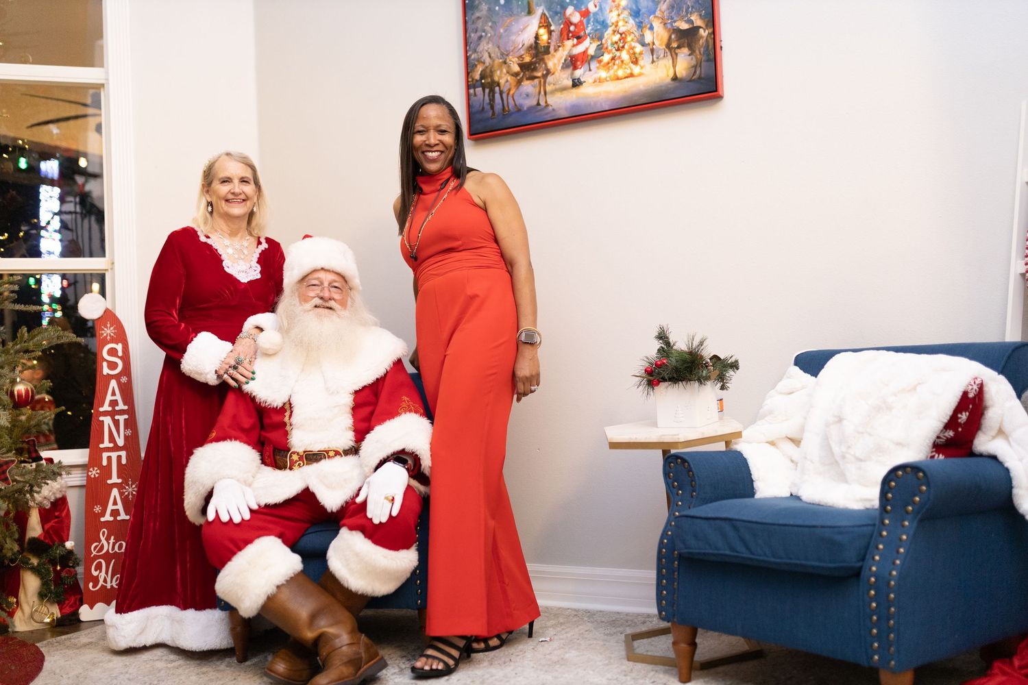 Santa Claus meets with visitors on blue chaise lounge during holiday photo session.