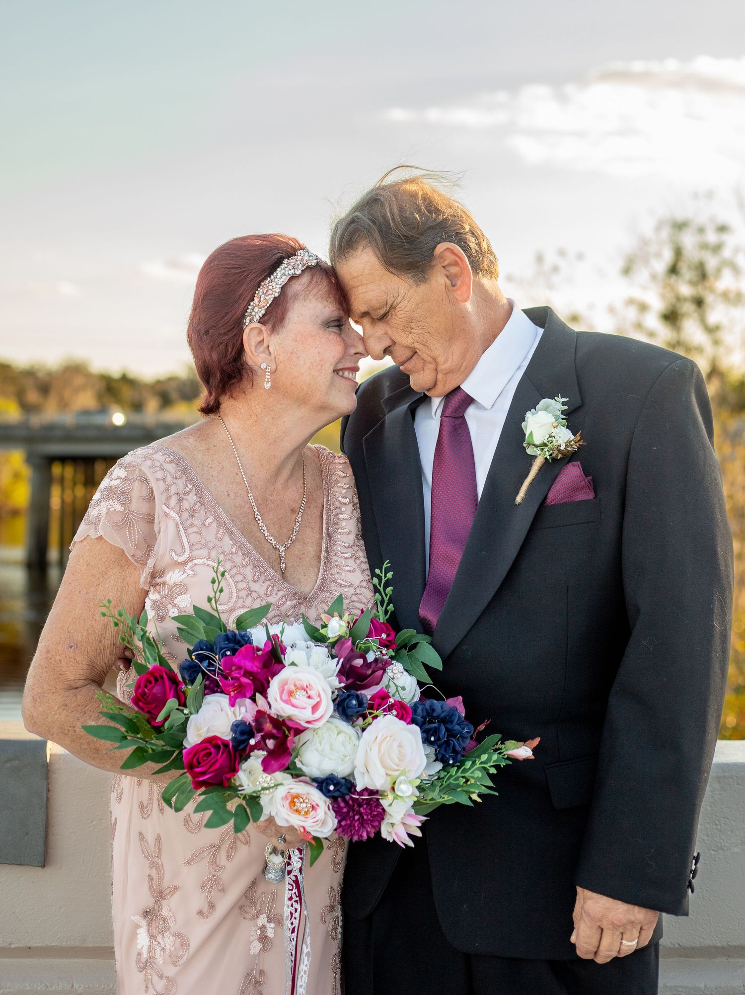 Romantic sunset wedding portraits with couple holding colorful bouquet.