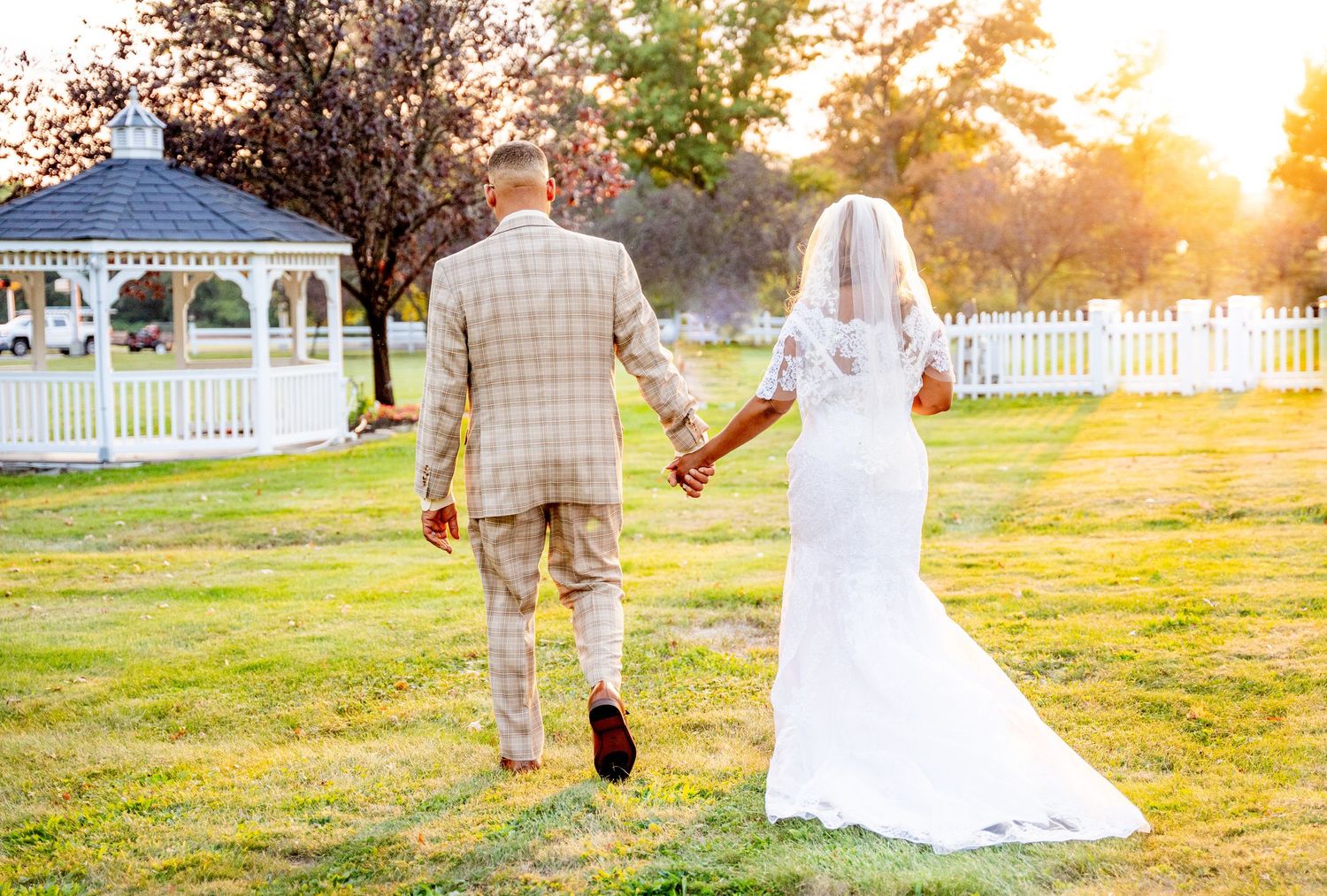 Couple walks together on grassy lawn during golden hour sunset in romantic wedding photo sequence.
