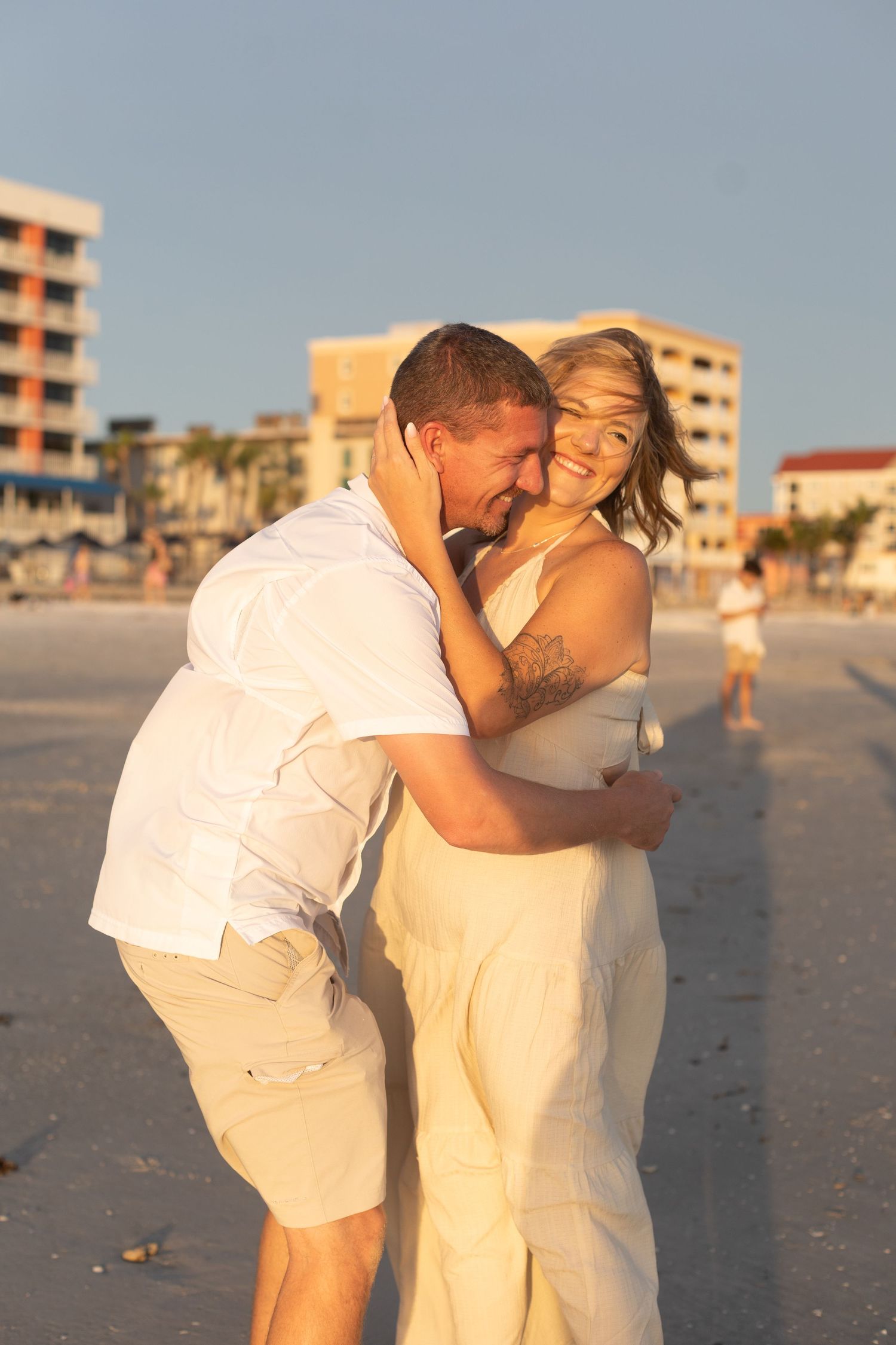 A couple shares an emotional moment after a beach proposal at sunset.