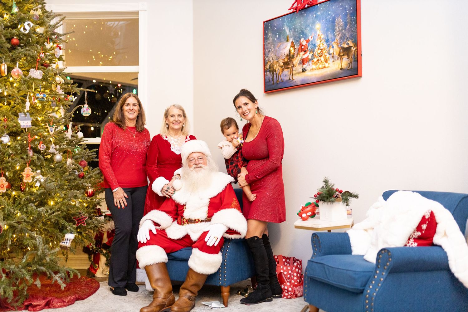 Holiday photo shoot with Santa and family posing playfully near decorated Christmas tree.