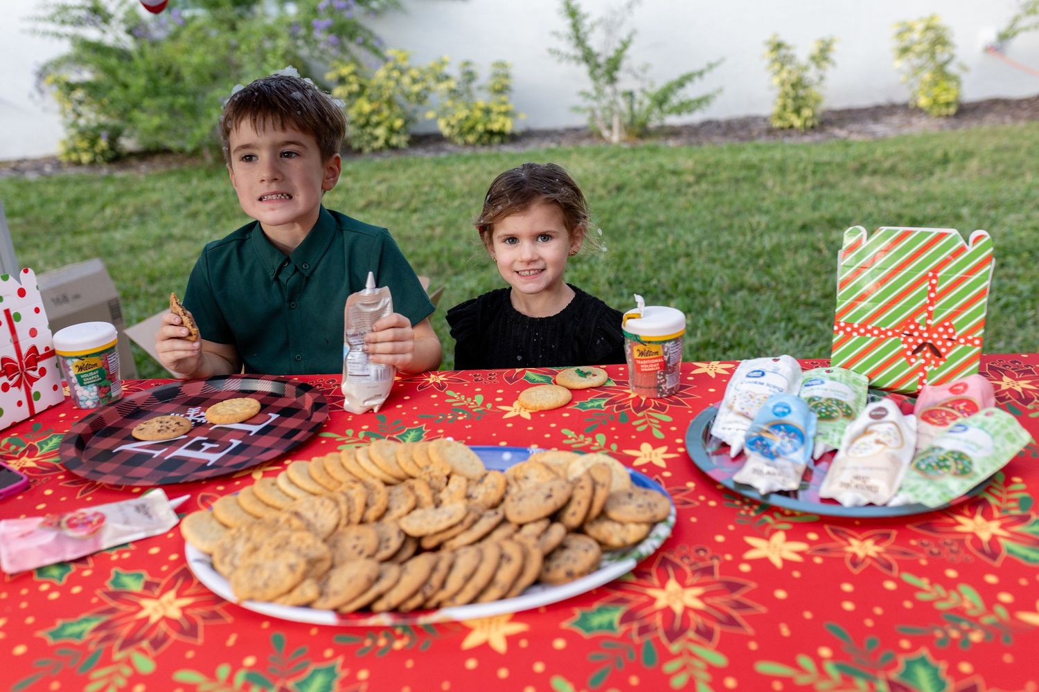 Holiday party setup with red tablecloth and festive decorations showing plates of cookies and snacks.