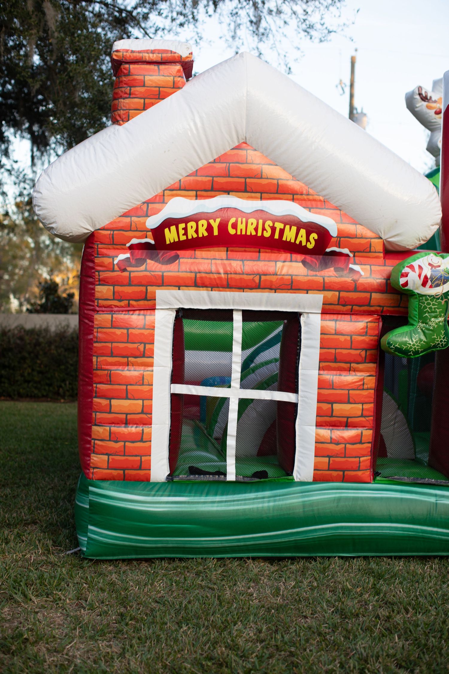 An inflatable Christmas house decoration with brick pattern and snow-covered roof.