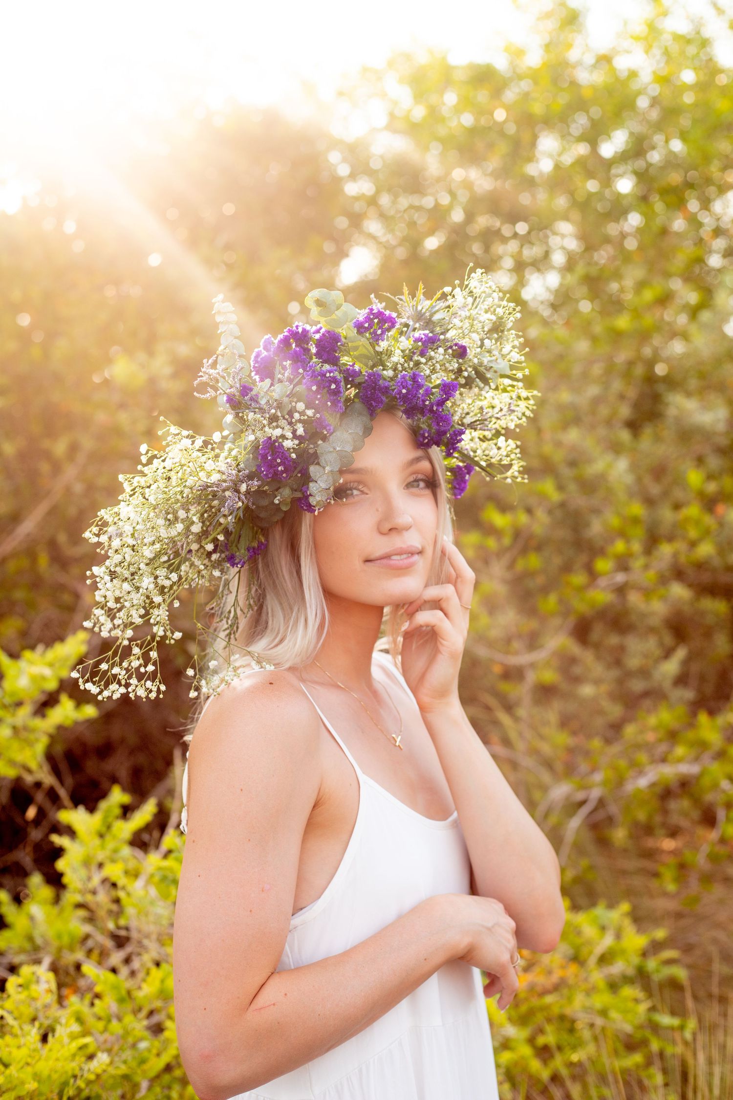 Ethereal summer portrait with a floral crown and white dress in golden sunlight.