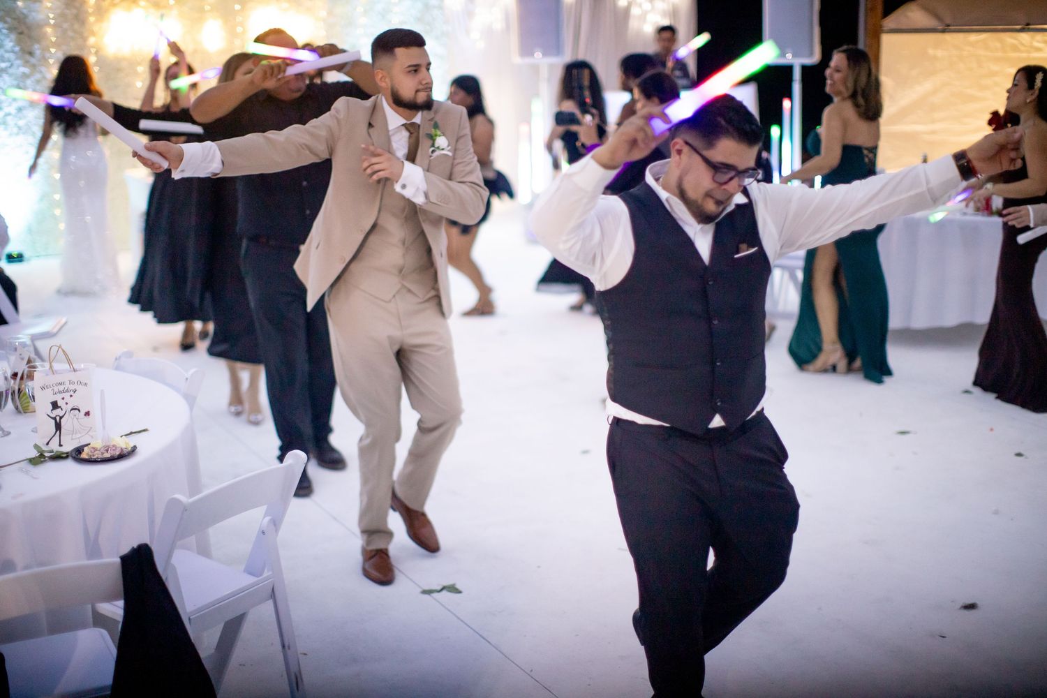 Wedding guests dancing and celebrating on a white dance floor at a reception.