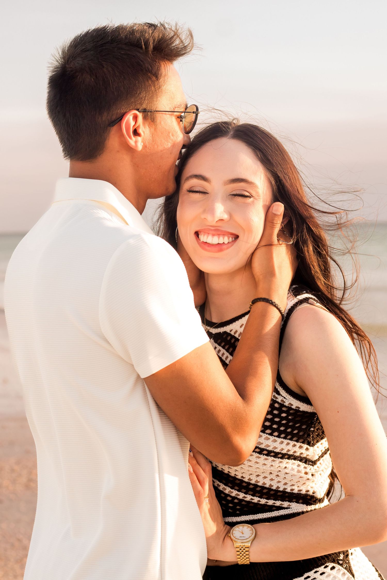 Couple sharing romantic moment during sunset beach photoshoot.