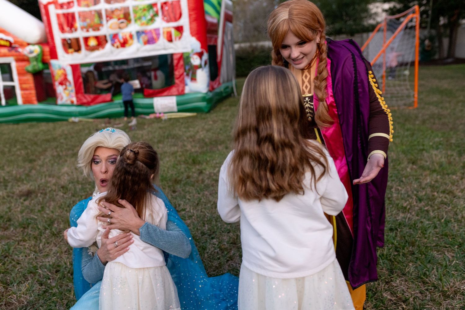 People in costumes interact at an outdoor carnival with food stands in the background.
