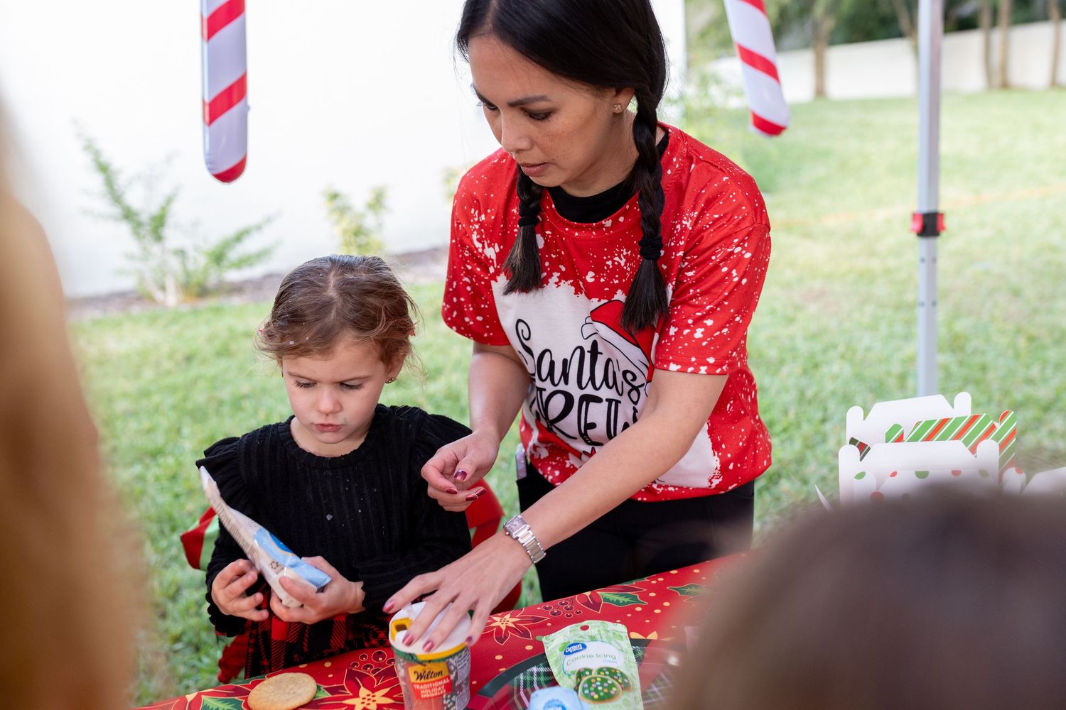 Holiday celebration under striped canopy with people enjoying snacks and activities.