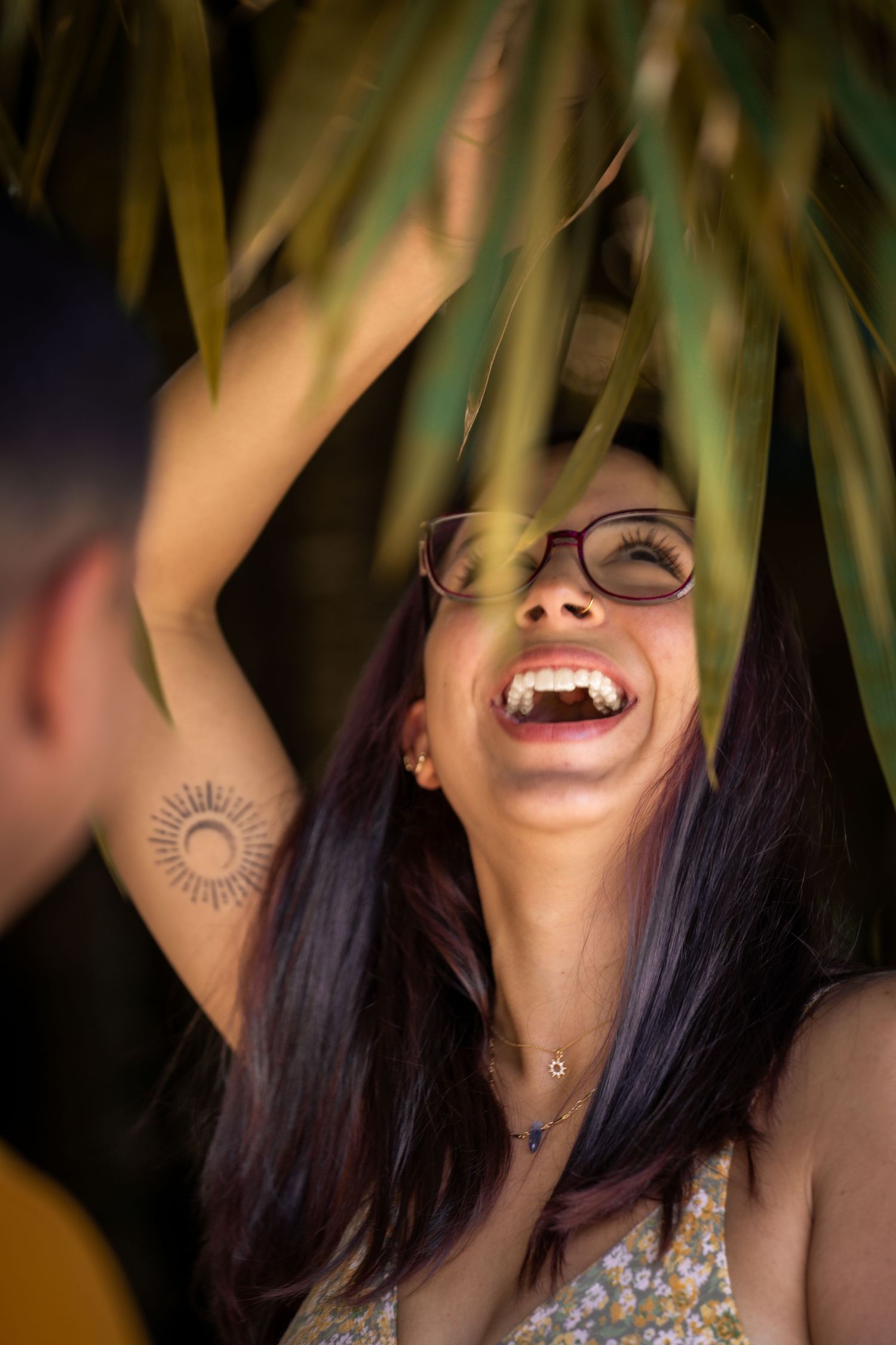 Woman laughing with joy while framed by green leaves.