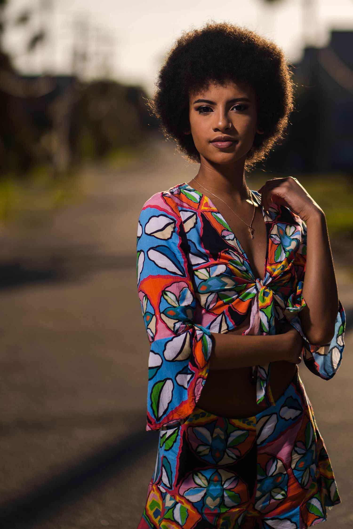 Woman in colorful outfit standing confidently on a quiet street.