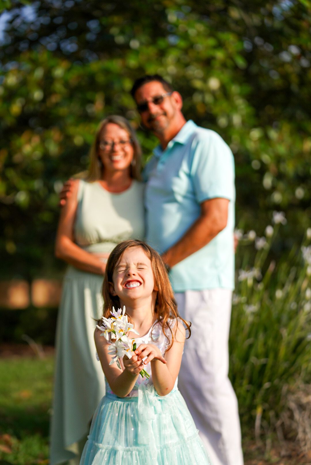 Family portrait with parents and young daughter in a park, dressed formally.