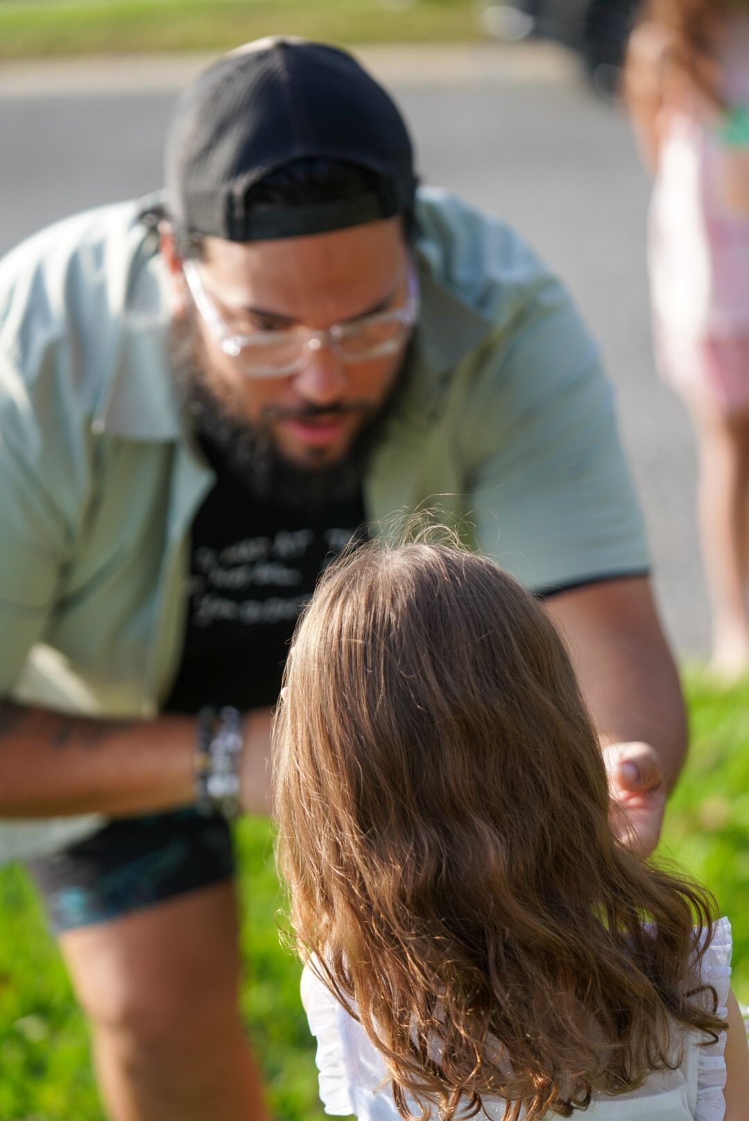 Father bending down to engage with his daughter in a park setting.