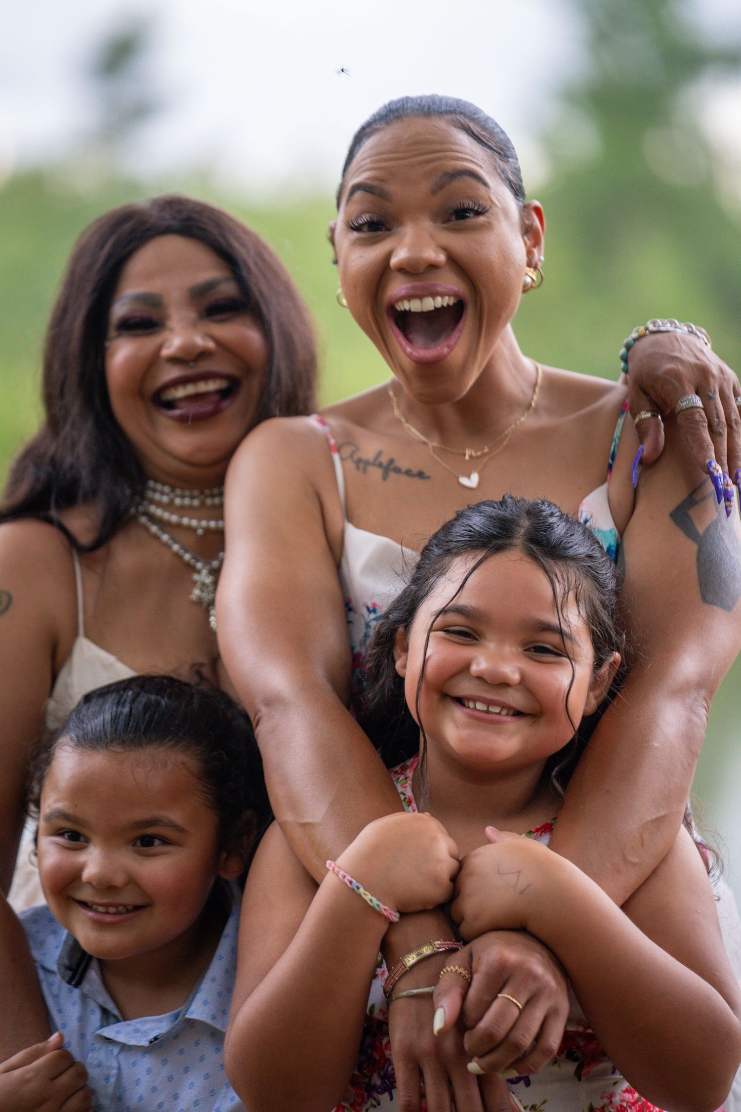 Mother laughing with three children during a joyful outdoor family moment.