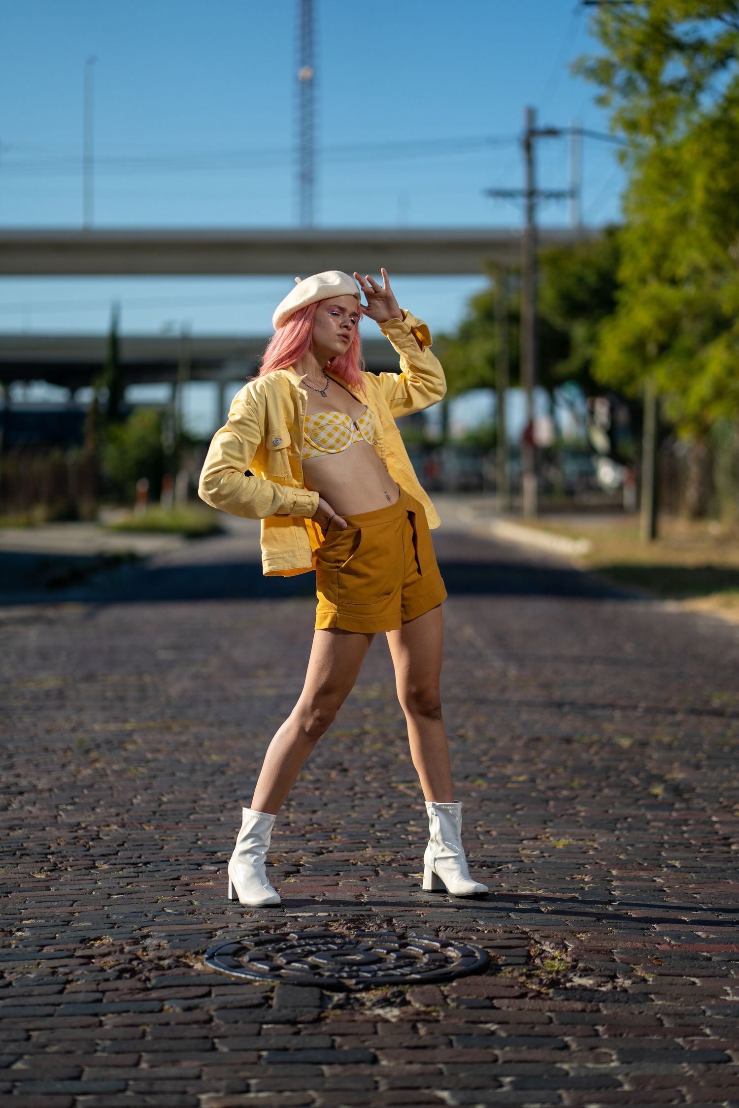 Woman in bright yellow jacket striking a confident pose on an urban street.
