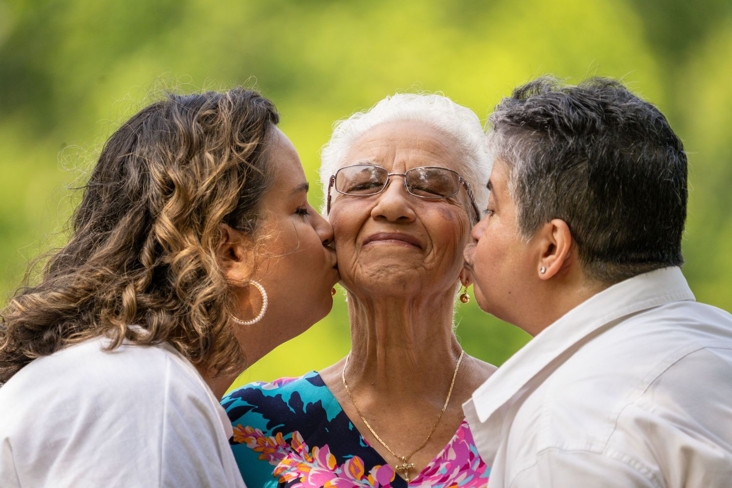 Grandmother receiving kisses on the cheek from two family members.