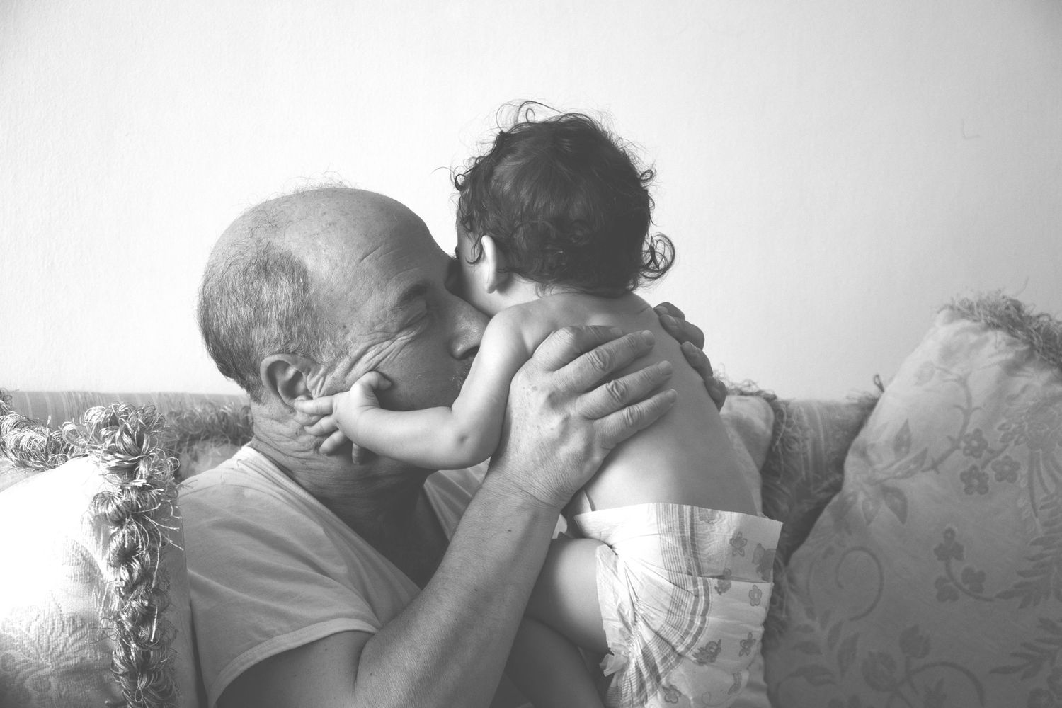 Grandparent kissing baby during a tender at-home family photography session