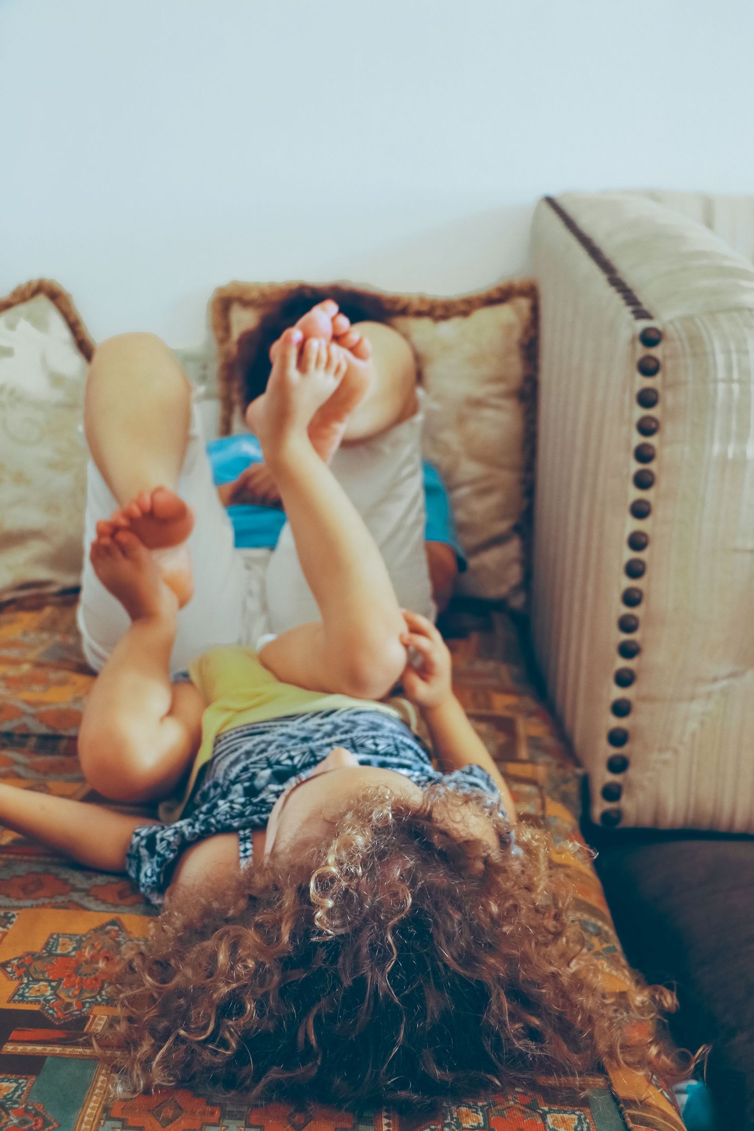Child playing upside down on a couch with her grandmother during an at-home family photography session  in Ottawa