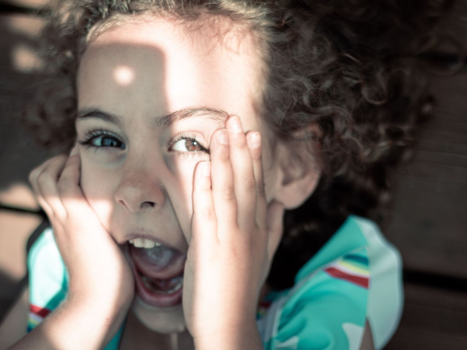Child laughing in window light during a playful at-home family photography session