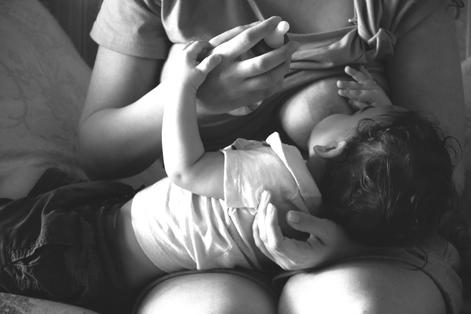 Baby breastfeeding while resting in a parent’s arms during an at-home family photography session in Ottawa