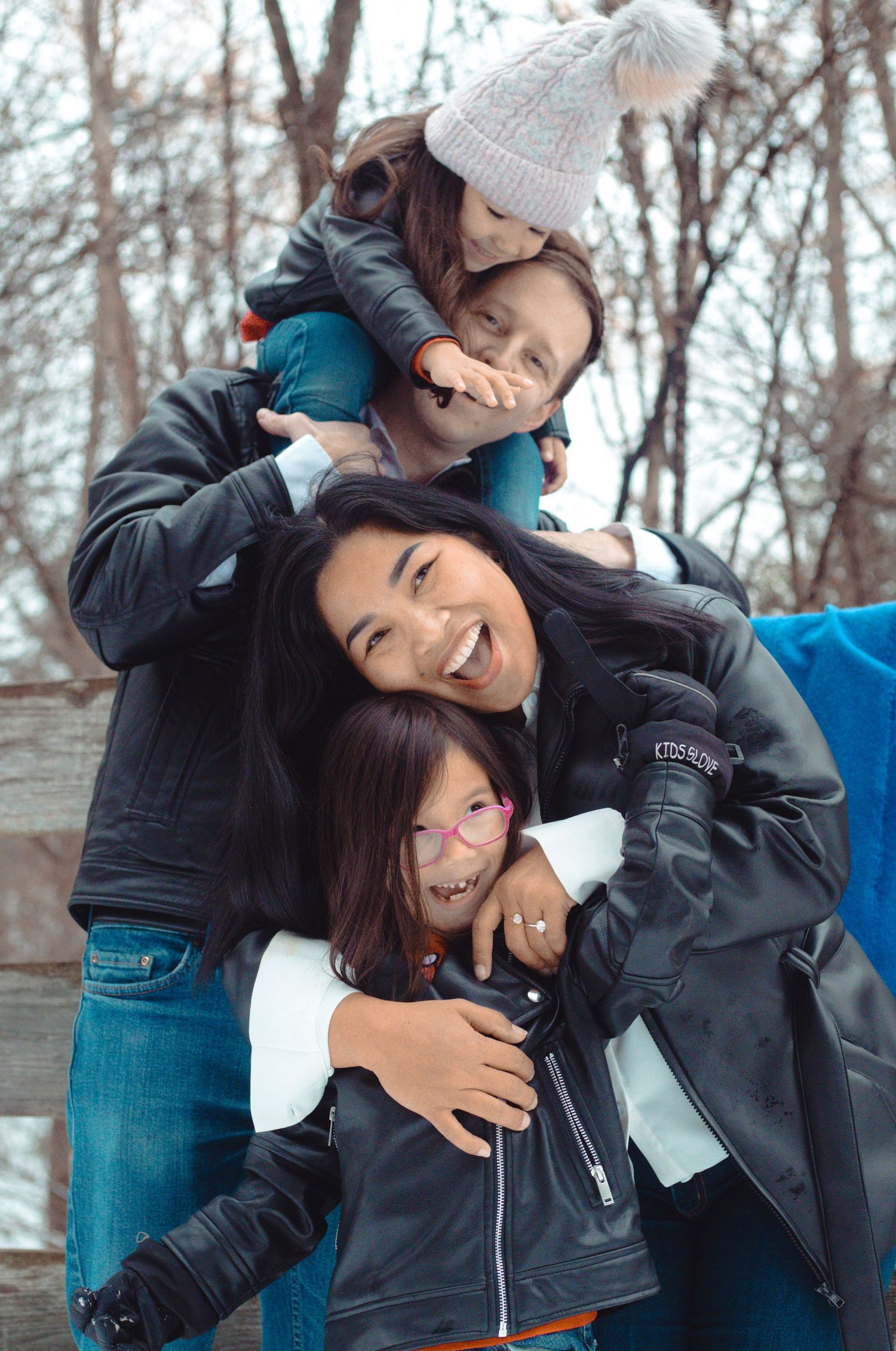 Father, mother, and two little kids playing together outdoors during a family photography session