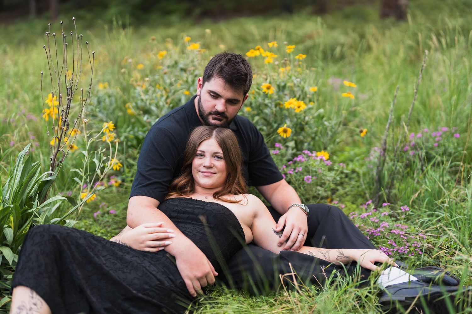 A couple laying against each other in a flower field during an engagement photoshoot on Mt Graham.