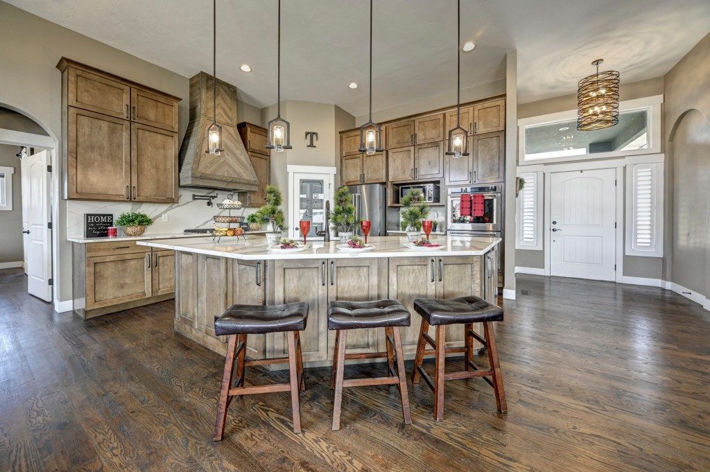 Spacious kitchen with wood cabinetry, large center island, bar stools, and pendant lighting.