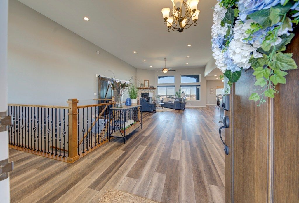 Bright open-concept entryway with hardwood floors, wrought iron staircase railing, chandelier, and view to living room.