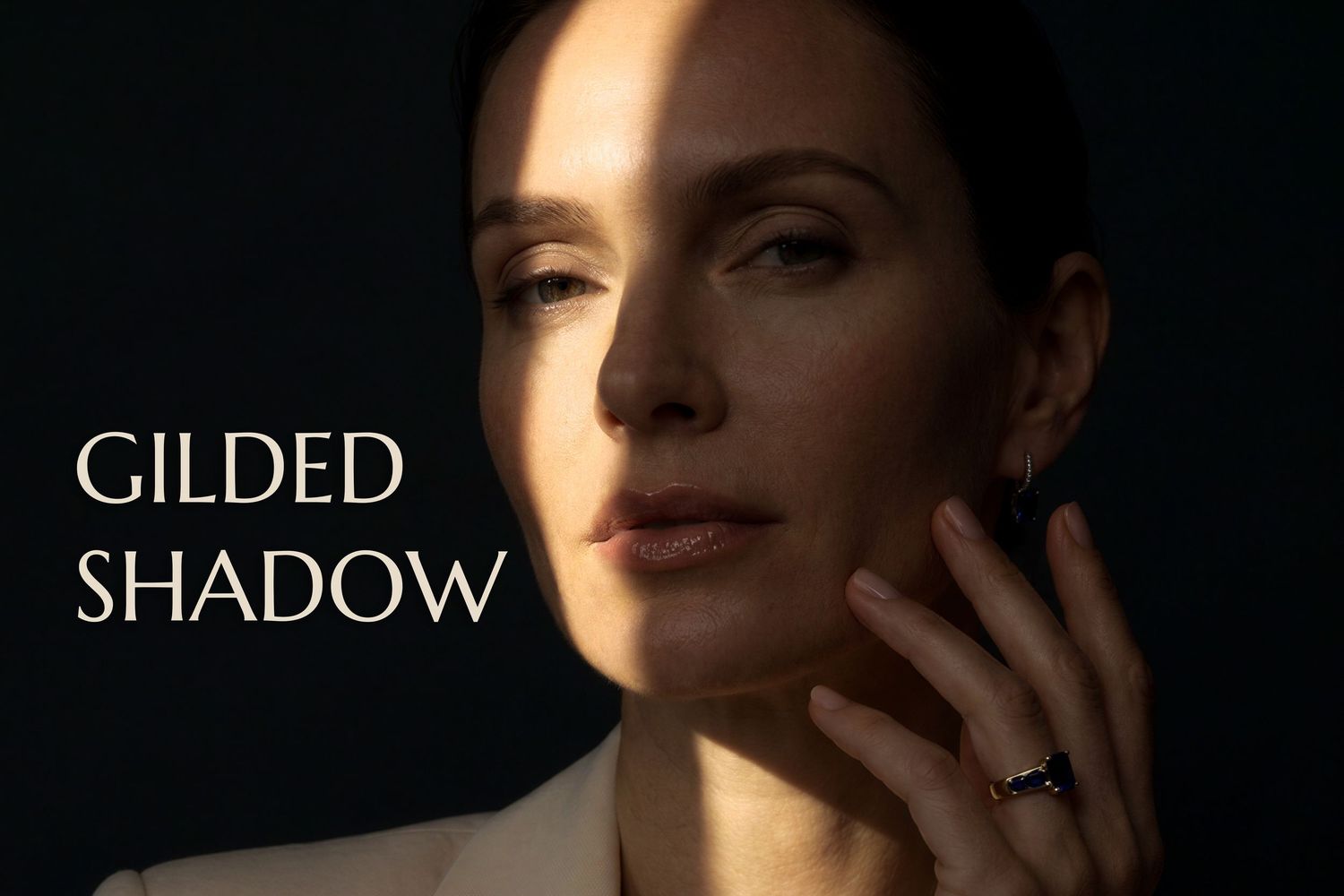 Woman in dramatic lighting with text Gilded Shadow, wearing a ring, elegant portrait photography.
