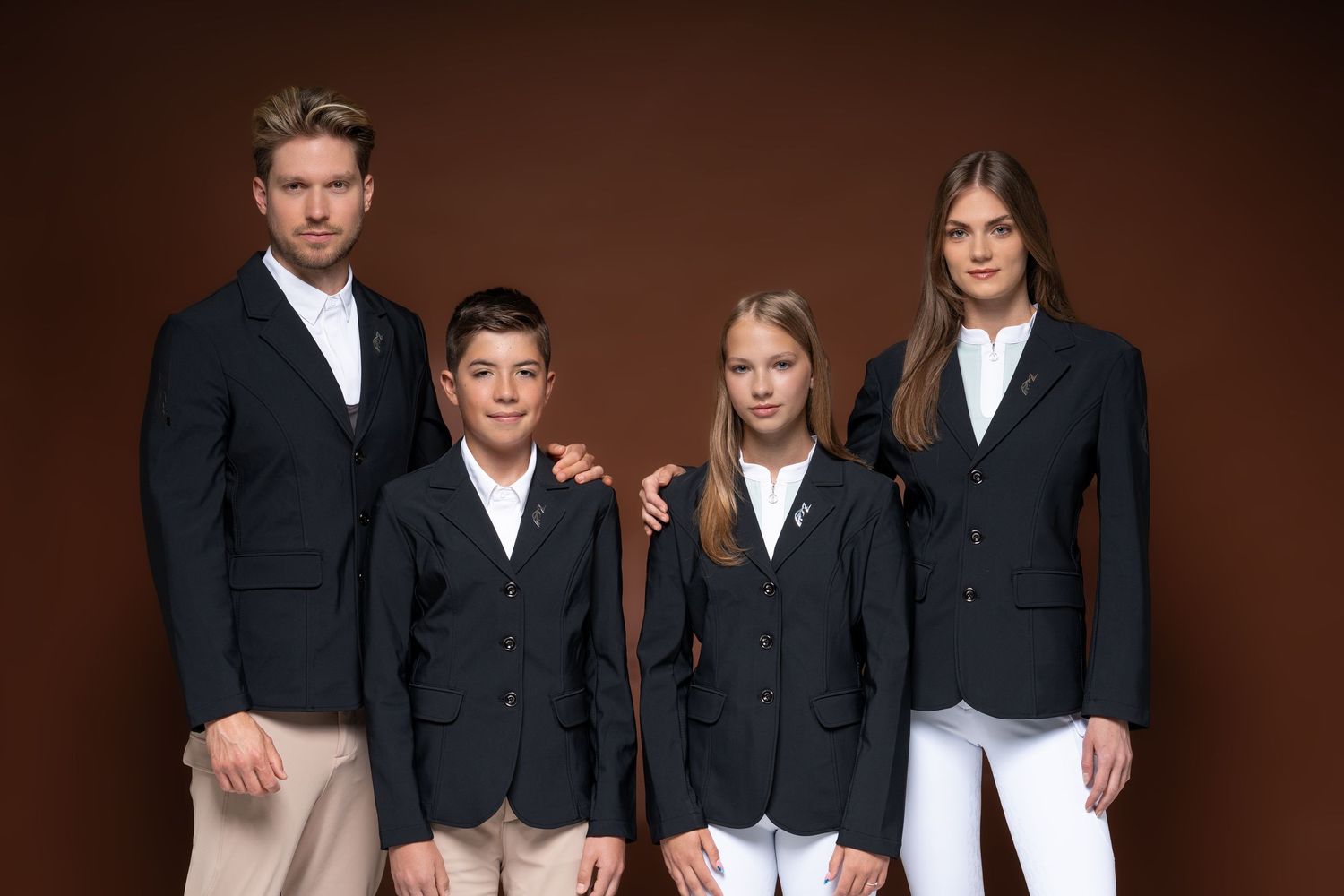 Family of four wearing matching navy Sally equestrian show jackets posing together on brown background.
