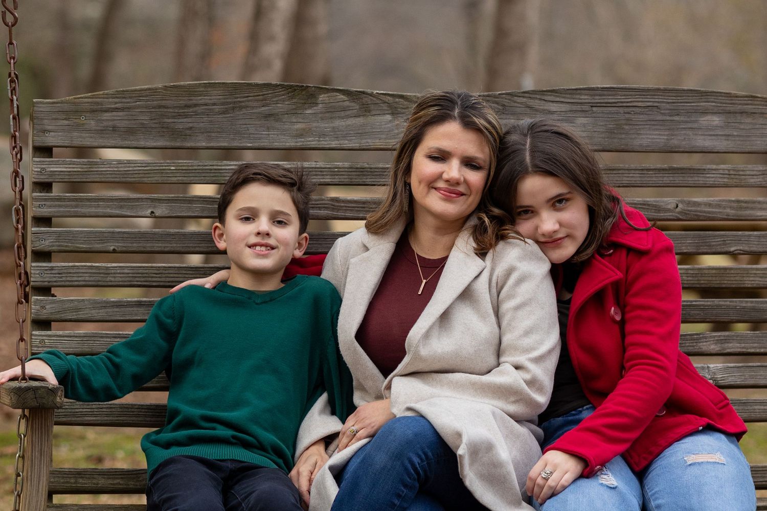 Mom on bench with kids — Mother sitting on a wooden bench with her son and daughter in a peaceful outdoor park.