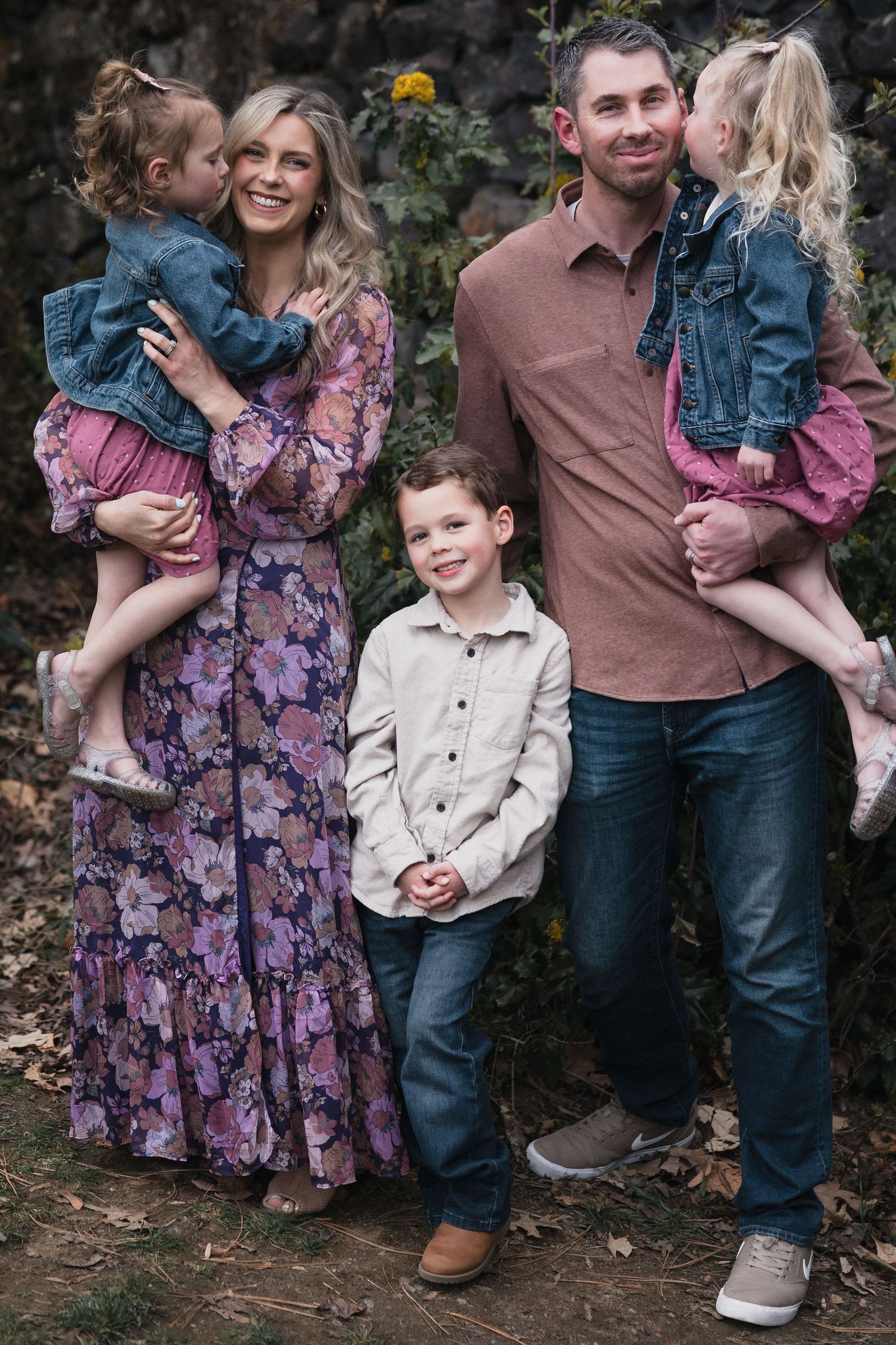 Family of five outdoors — Family of five posing outdoors, parents holding two girls in denim jackets with their son standing between them.