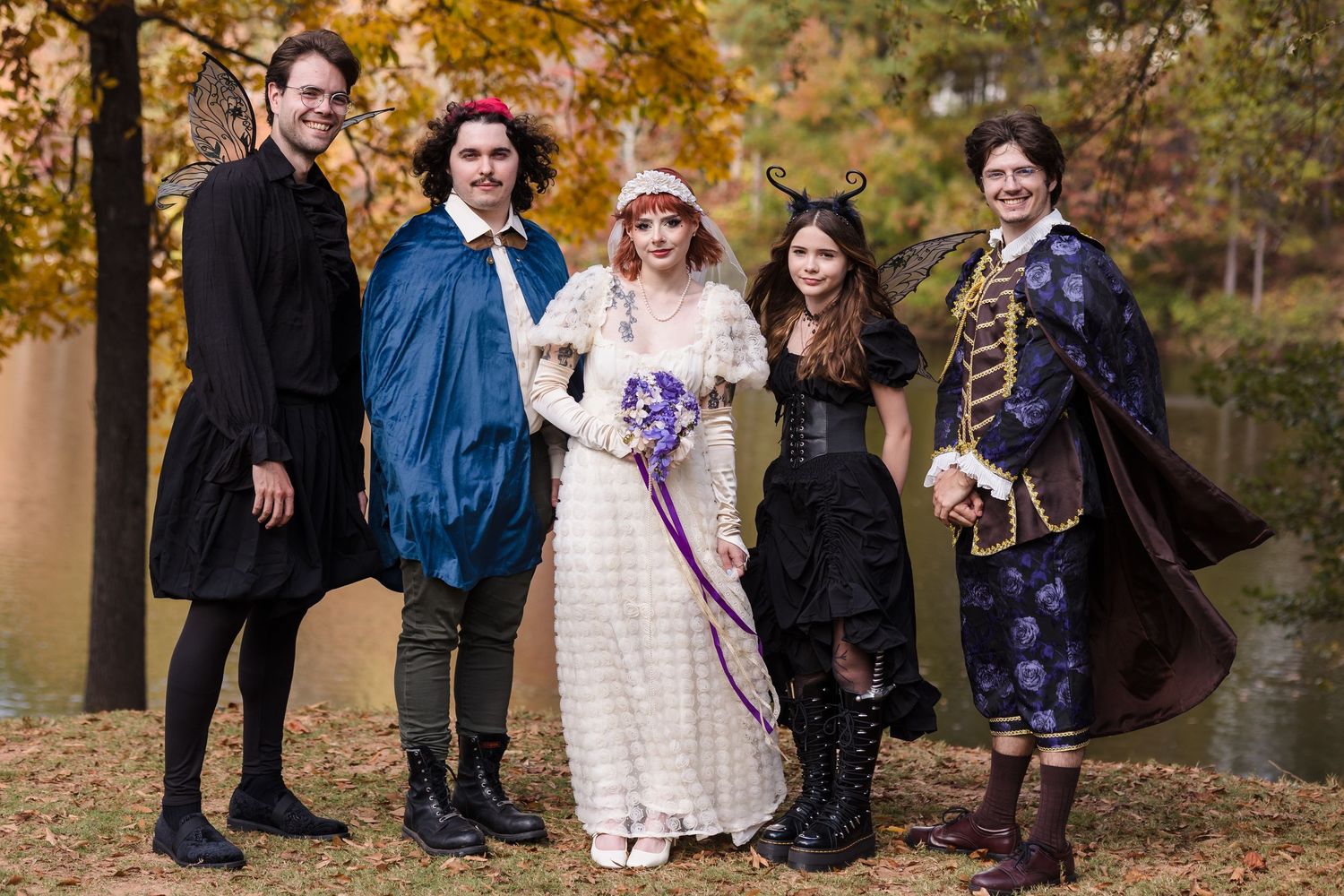 Group of five people in fantasy and period costumes pose together at autumn outdoor wedding.