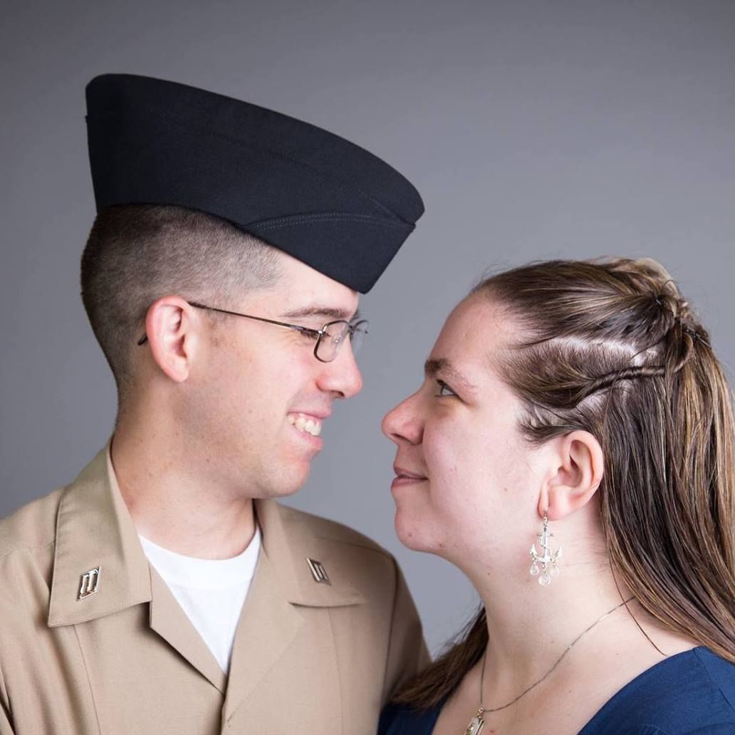 Military couple gazing — Military man in uniform and woman gazing at each other against a soft gray background.