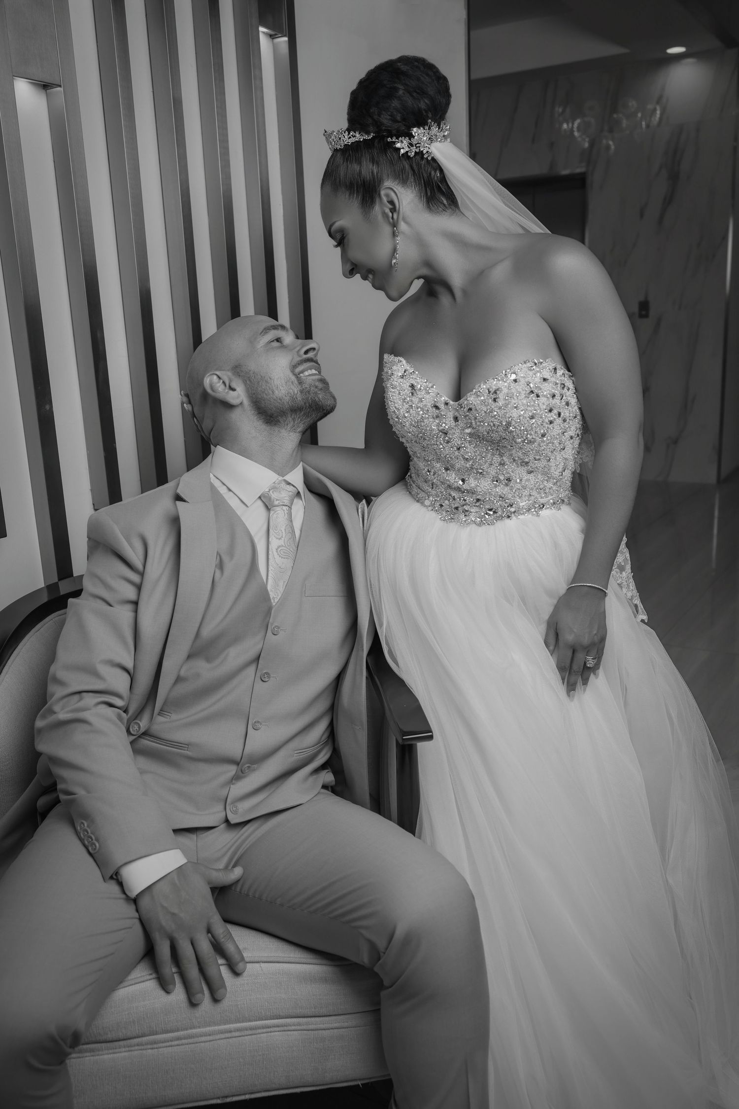 Black and white portrait of a bride looking down lovingly at her groom sitting beside her