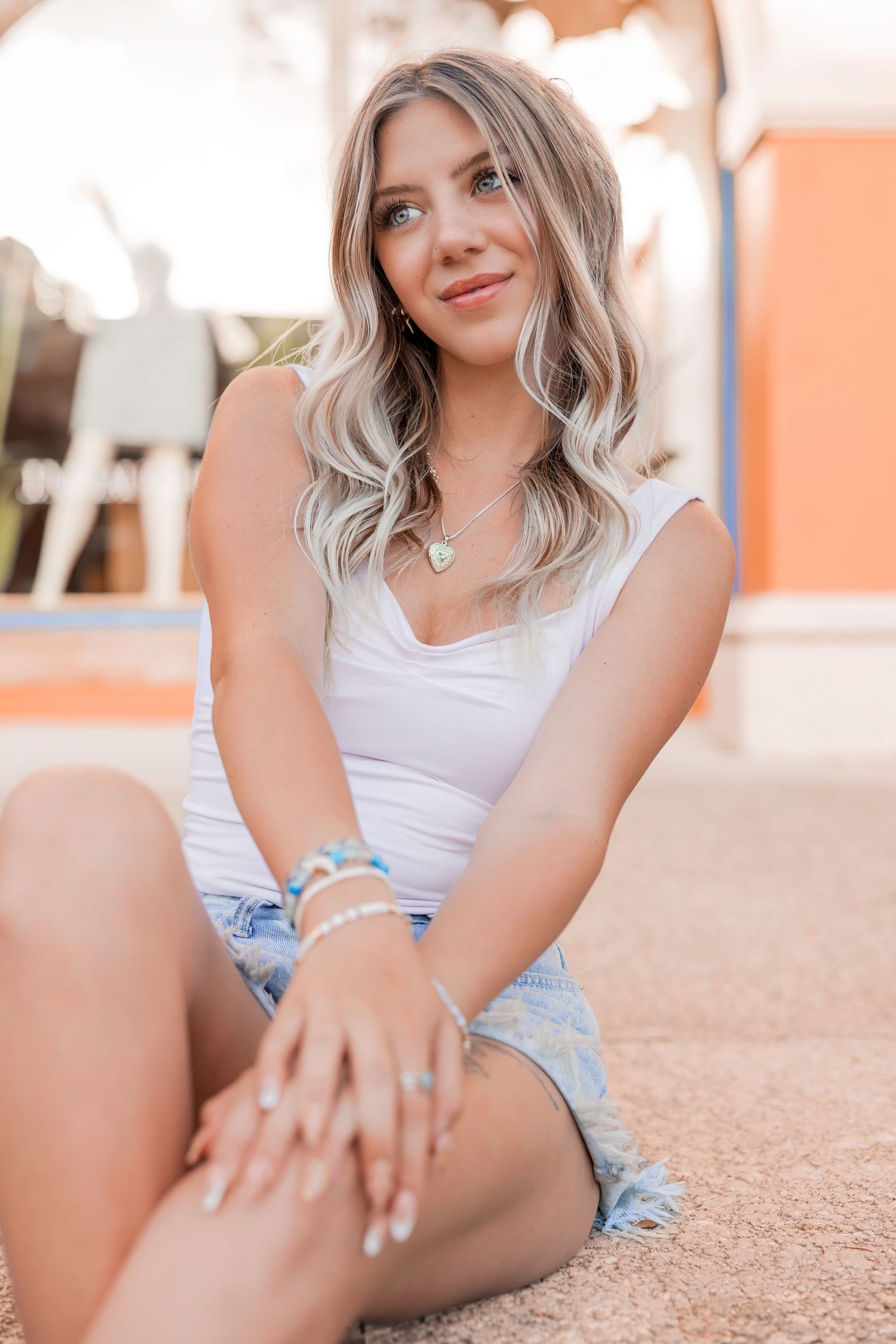 Smiling blonde woman sitting on outdoor steps wearing a casual light blue dress