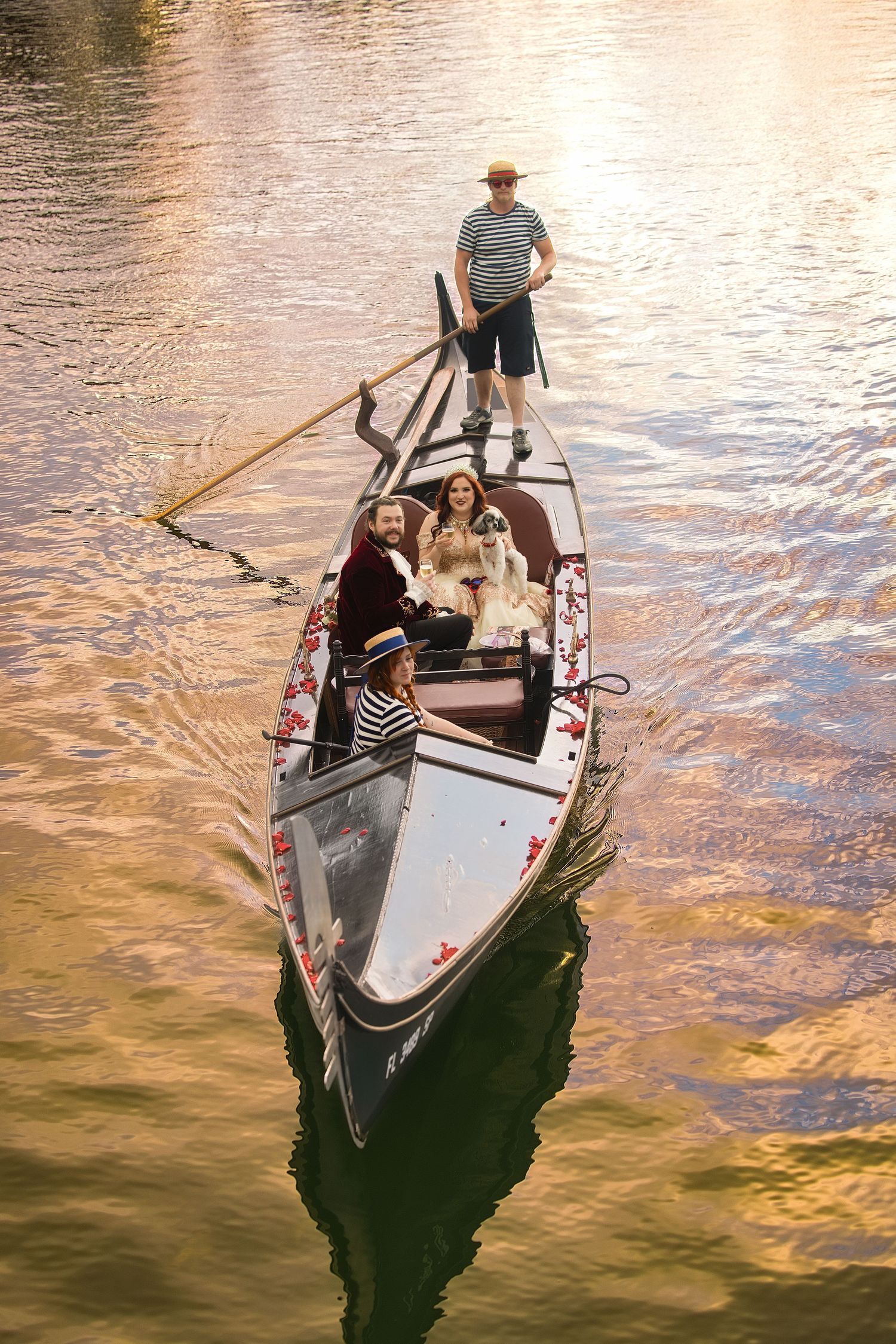 Gondolier rowboat carrying passengers down a river path illuminated by a golden sunset.