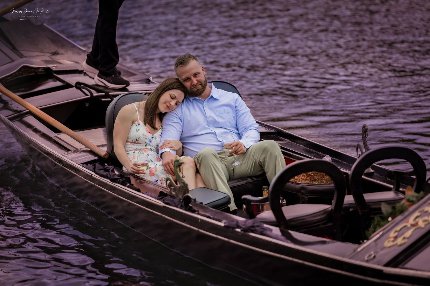 Couple sitting face-to-face sharing an intimate moment inside a gondola boat on the river