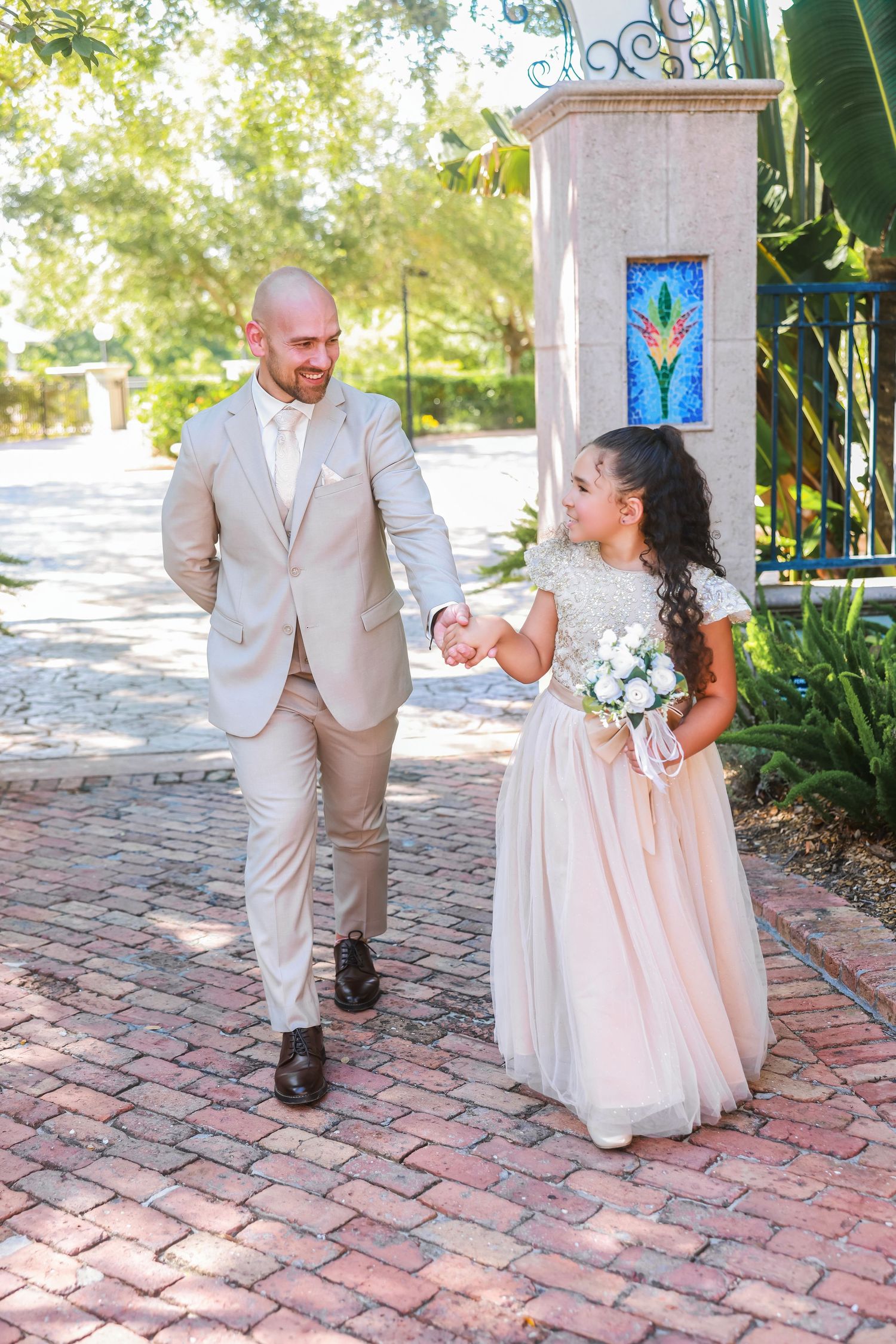 Bride and groom walking down a brick pathway outdoors while smiling after their wedding ceremony