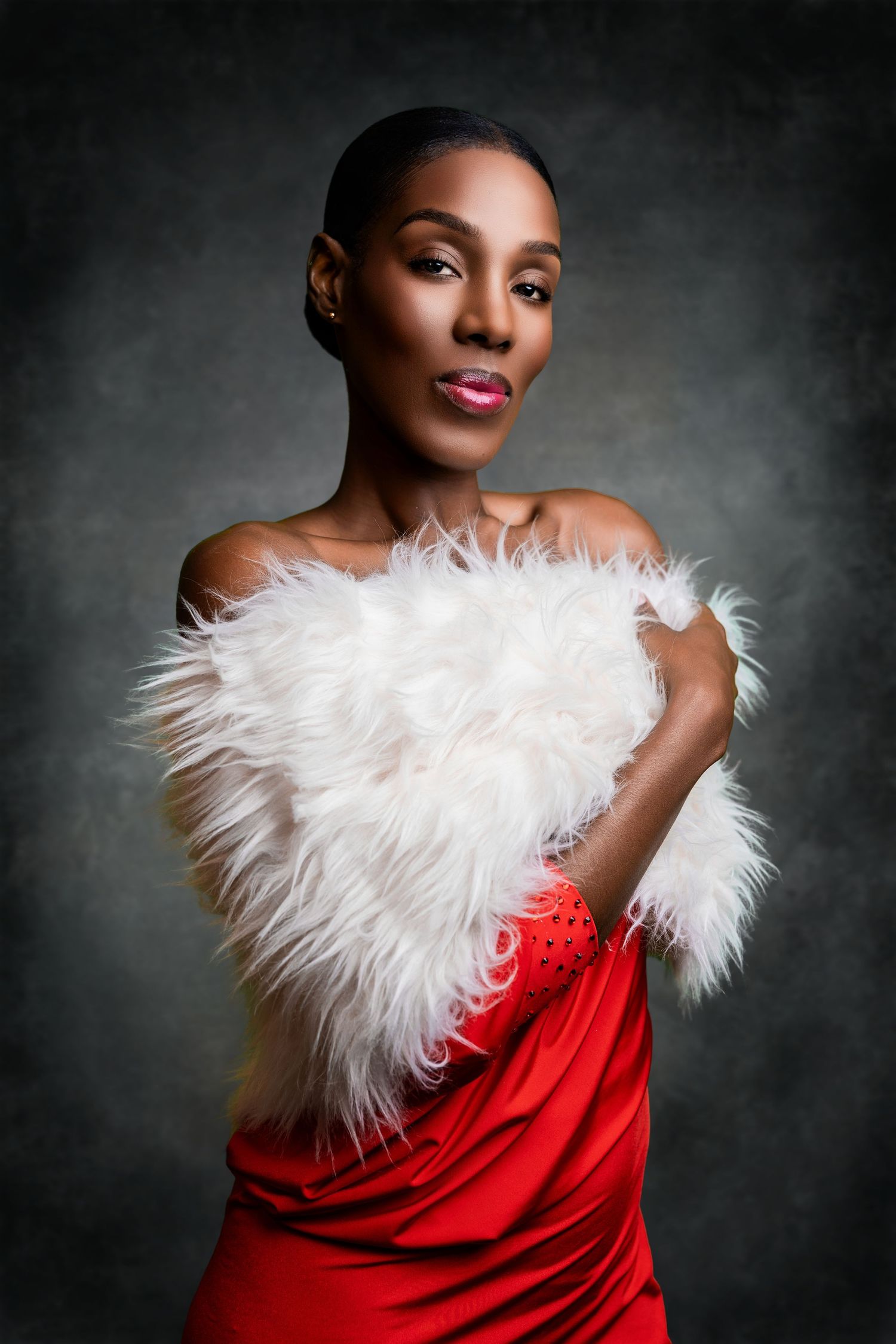 Glamour studio portrait of a woman wearing a red dress draped with a white feather wrap