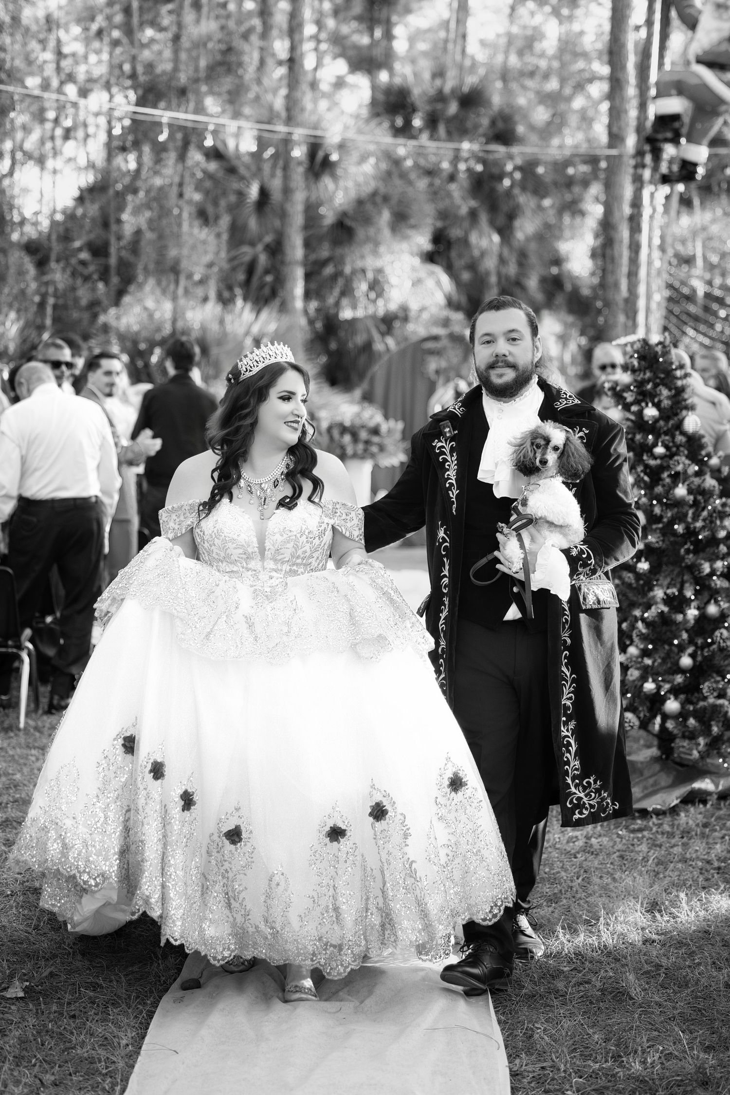 Black and white photo of a newlywed bride and groom walking down the outdoor ceremony aisle smiling