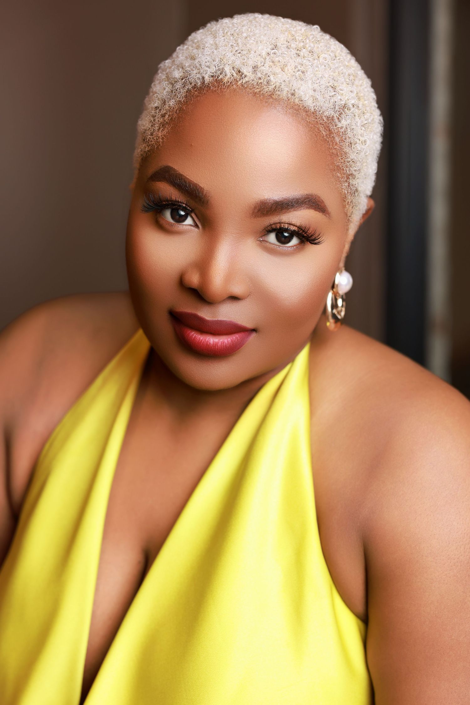 Close-up headshot of a woman with short blonde hair wearing a bright yellow halter top