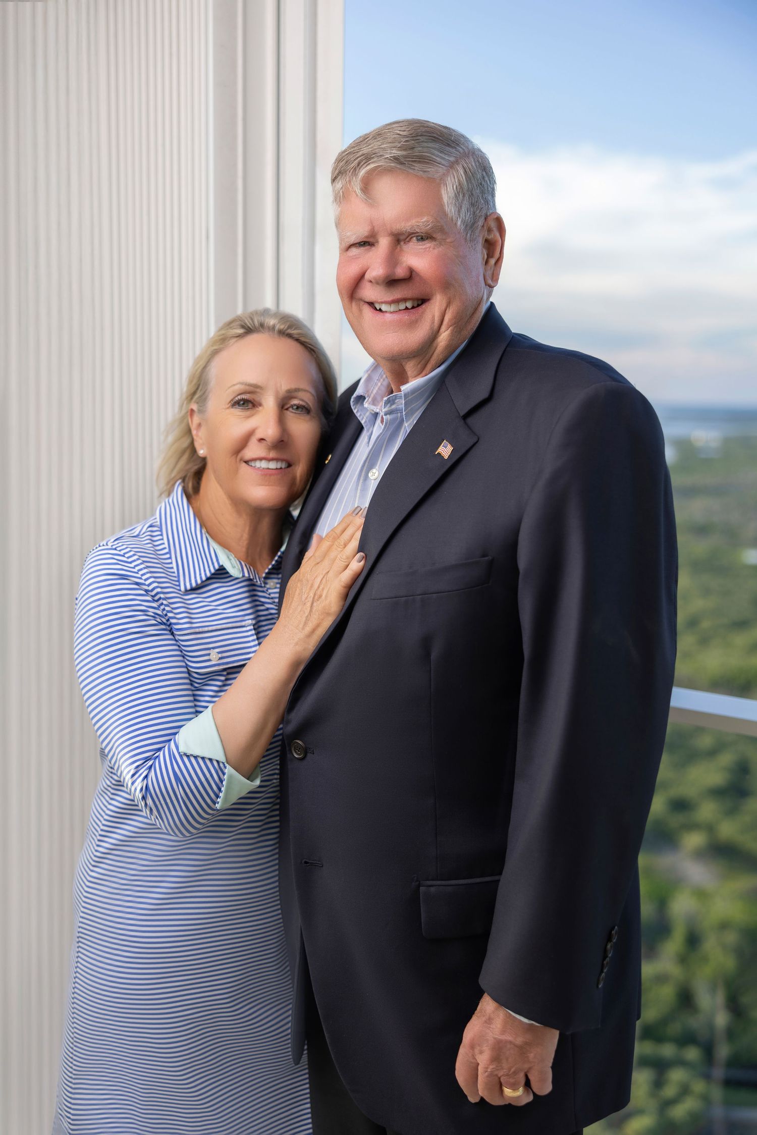 Smiling senior couple embracing outdoors against a scenic green background