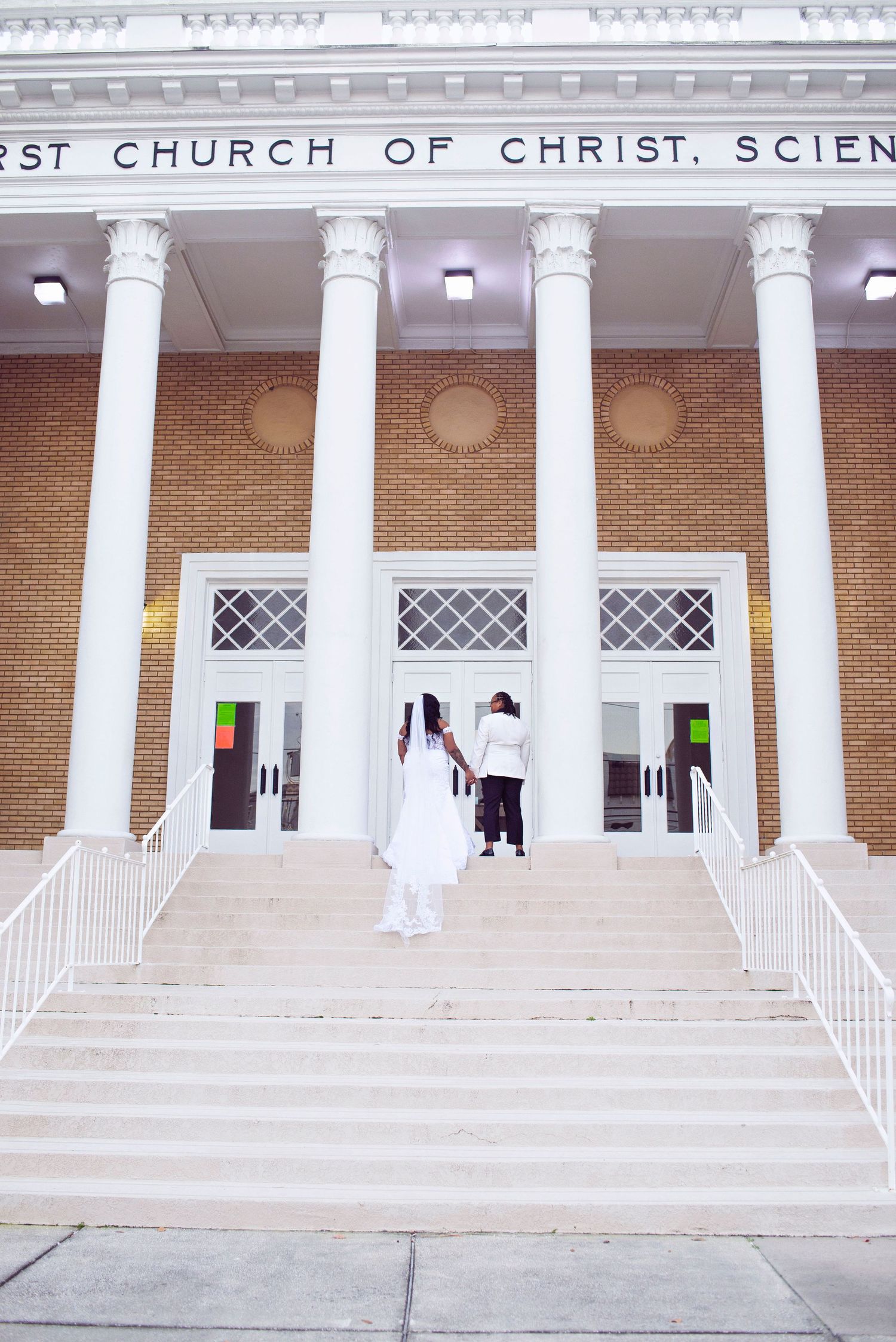 Wedding couple walks hand in hand up steps of First Church of Christ Science building.