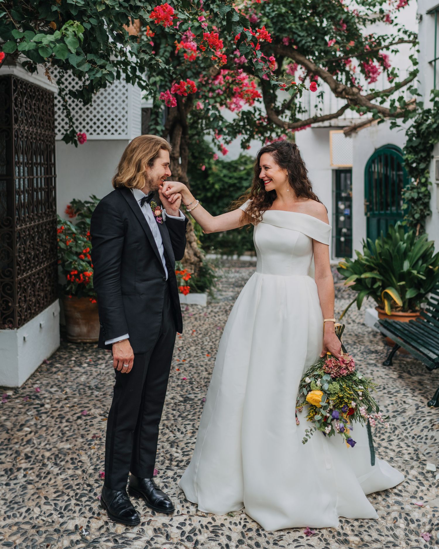 A romantic wedding moment in a courtyard with blooming bougainvillea and stone pathways.