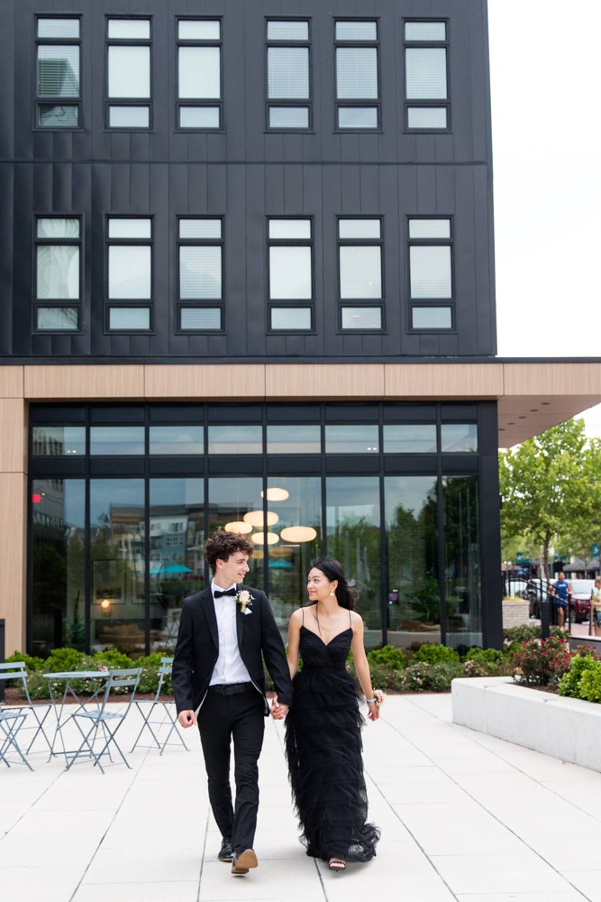 RVA Richmond Virginia portrait photographer. Personality filled photography. Young couple in formal attire walking in front of modern shop.