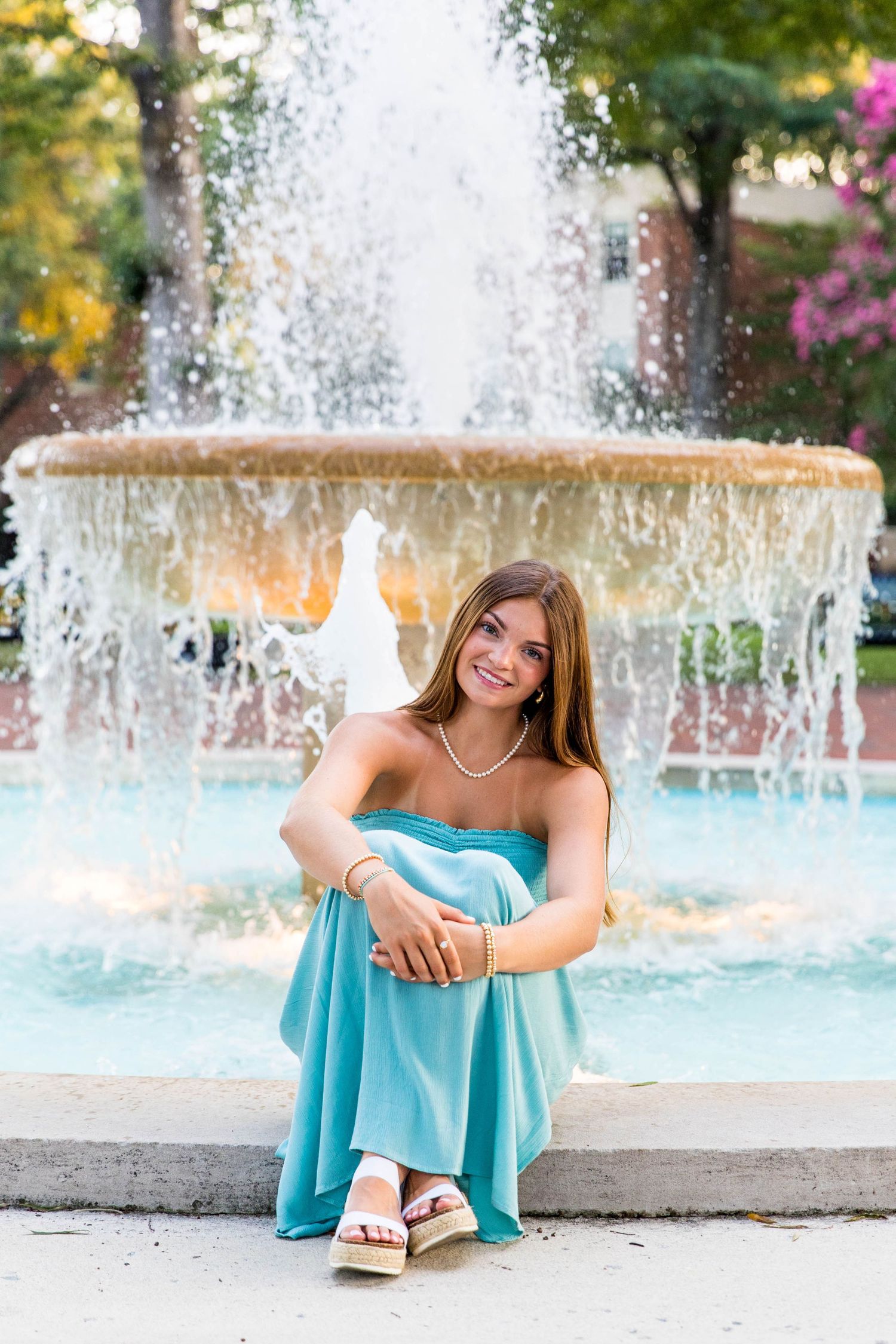 RVA Richmond Virginia senior photographer. Young woman in a blue dress sitting in front of a large fountain. RVA senior photography.