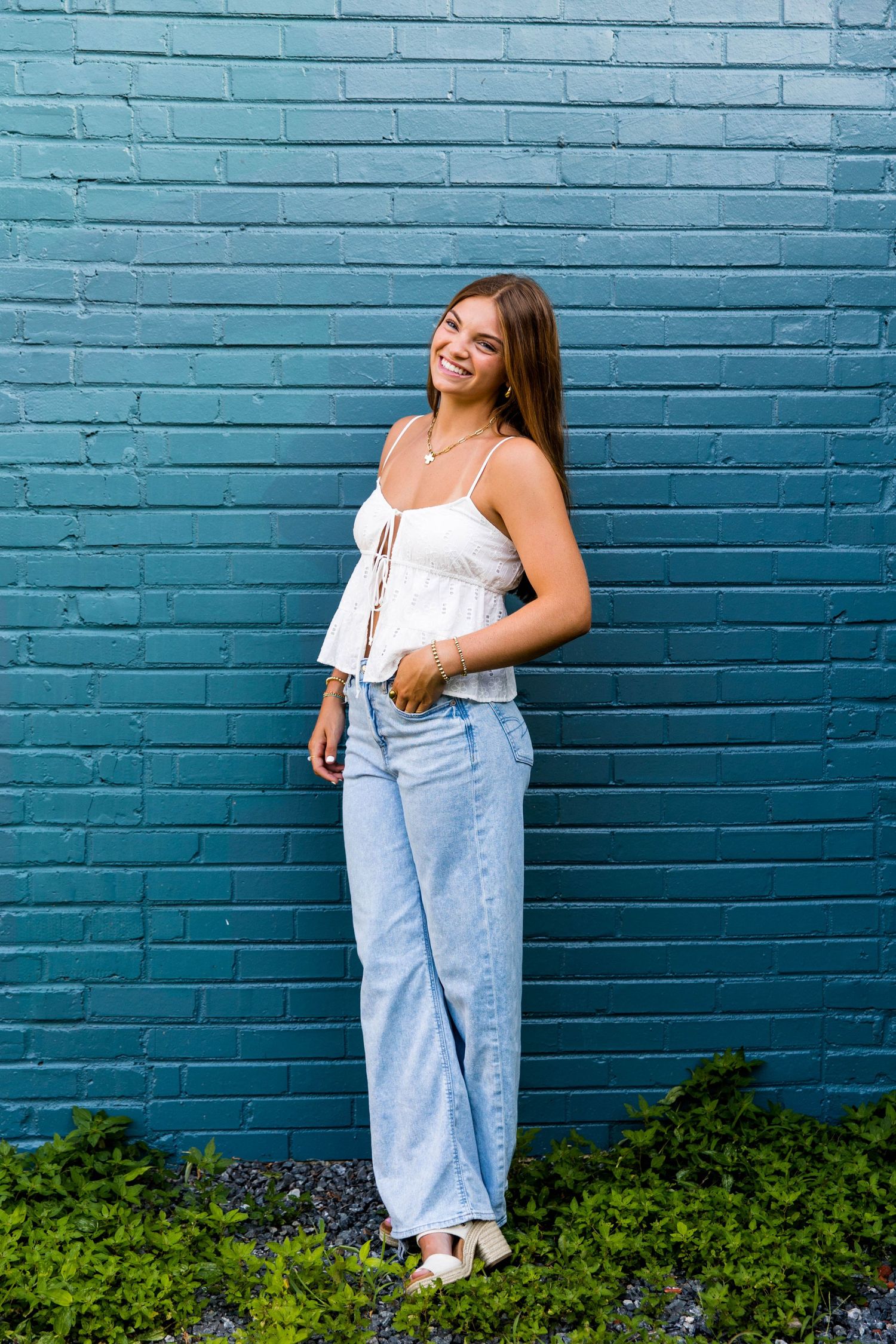 RVA Richmond Virginia senior photographer. Young woman standing in front of a teal brick wall. Richmond, Virginia senior photography.