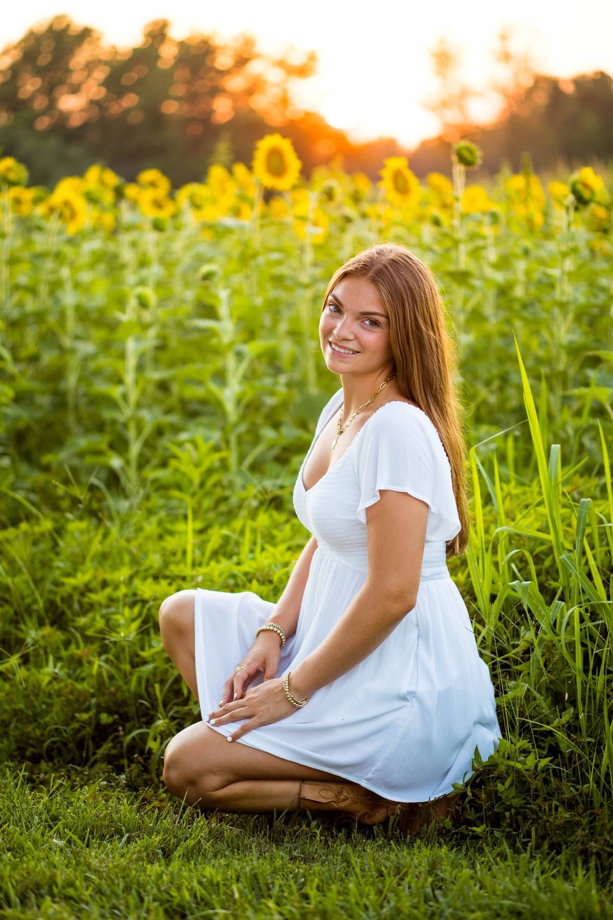 RVA Richmond Virginia senior photographer. Teen girl wearing a white dress in a field of sunflowers.